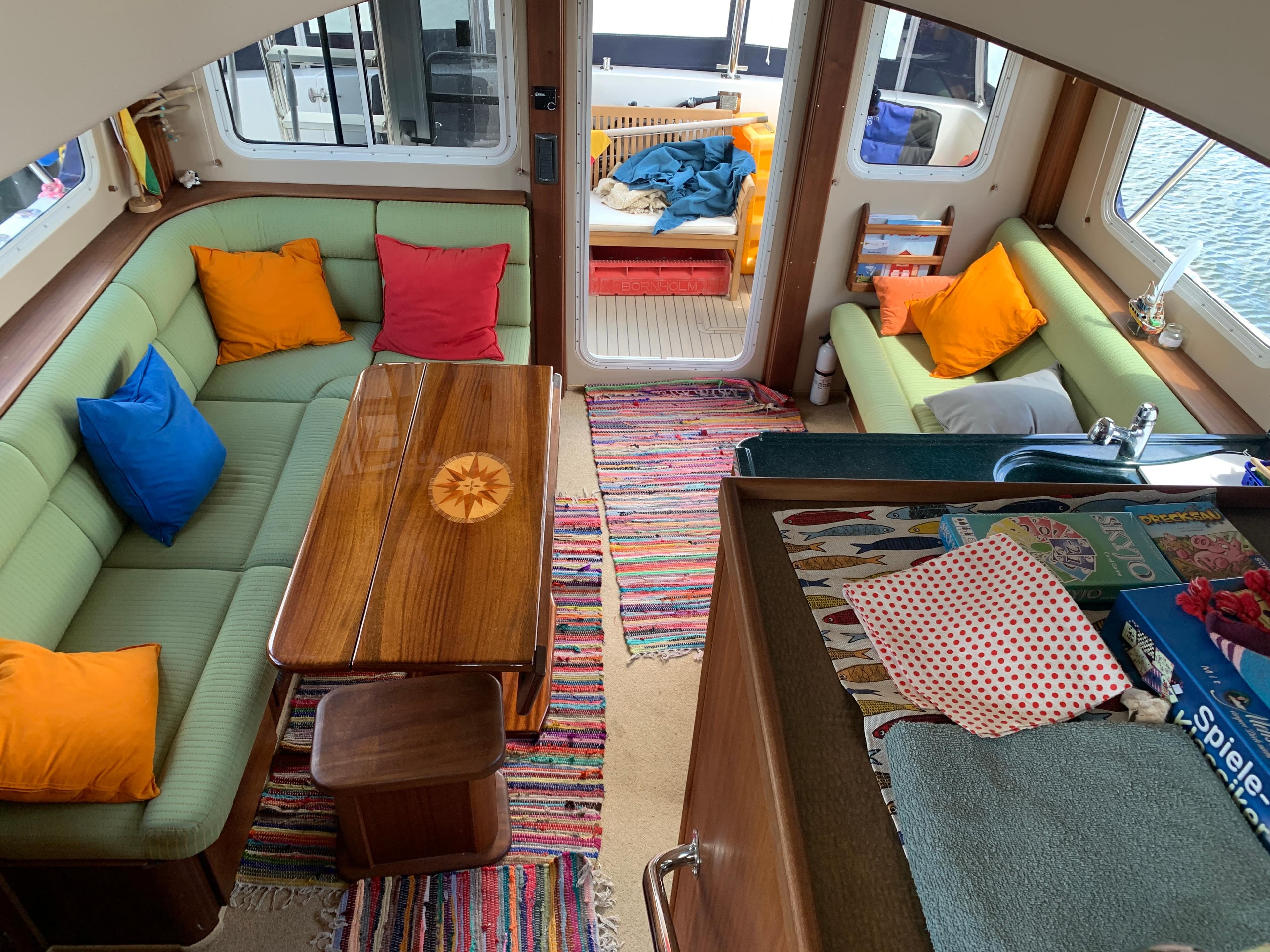 Interior of 2010 American Tug 41 with colorful cushions and wooden table.