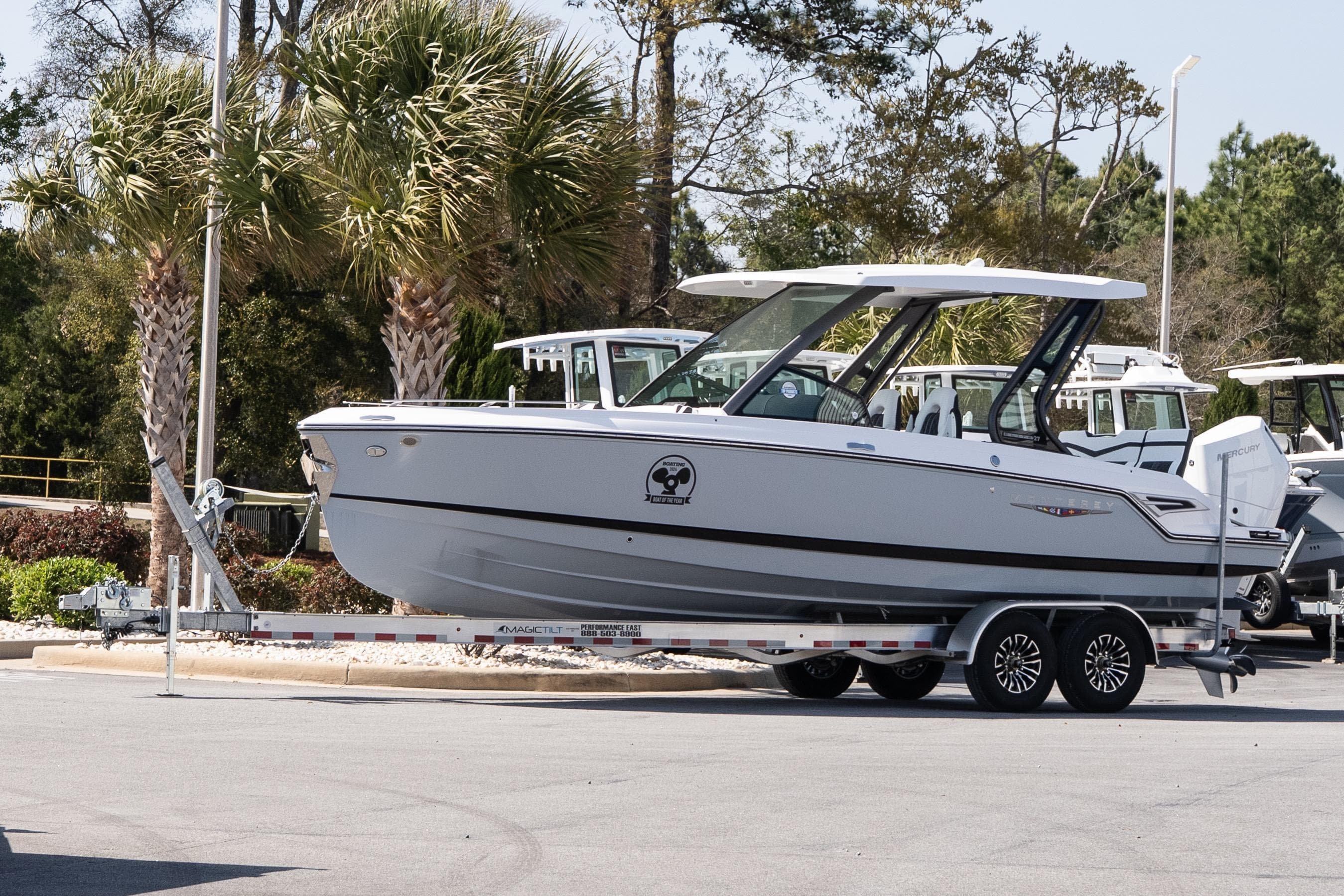 2026 Monterey Elite 27 OB boat on trailer, parked near palm trees.