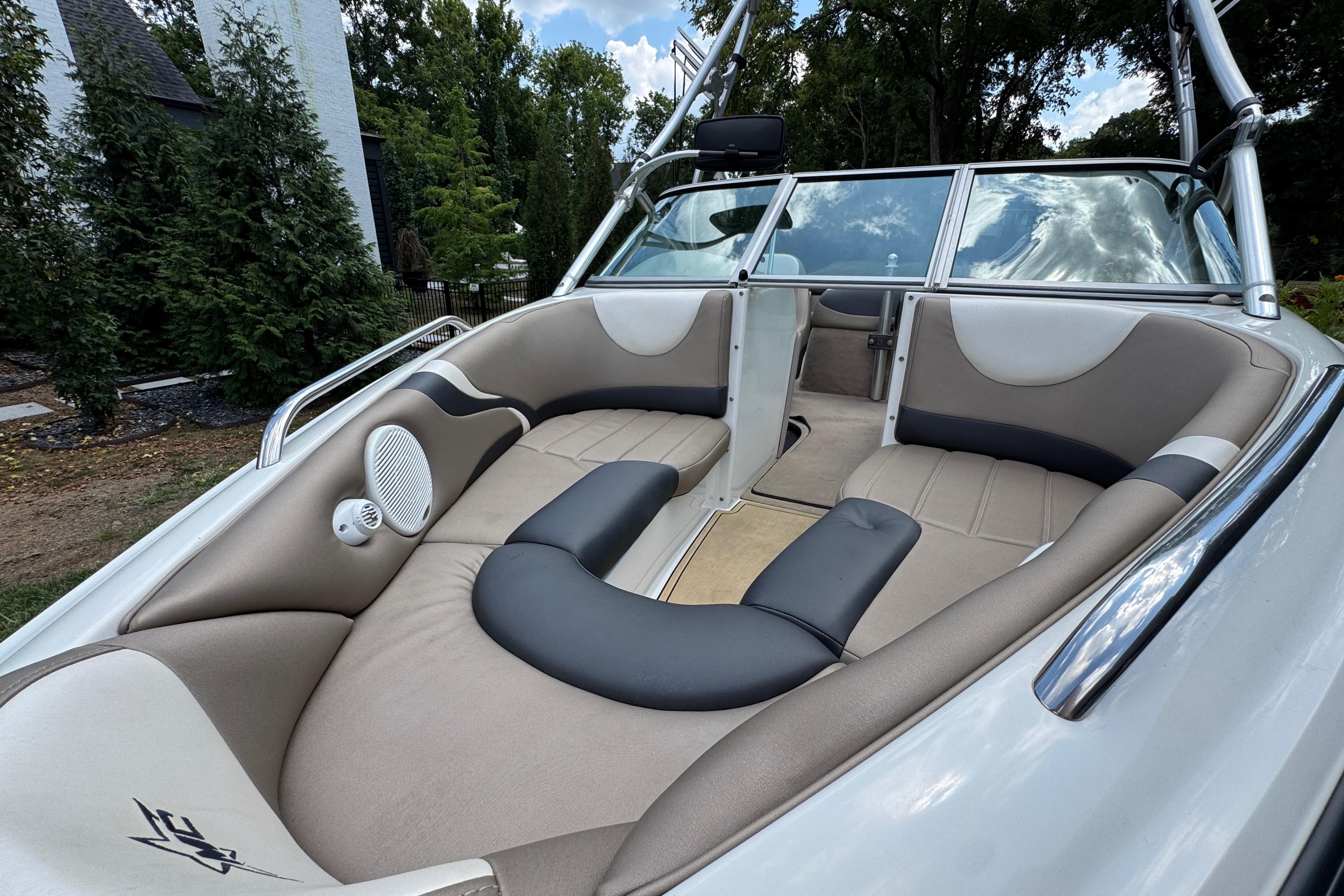 2002 MasterCraft ProStar 209 boat interior with beige seating and speaker, surrounded by trees.