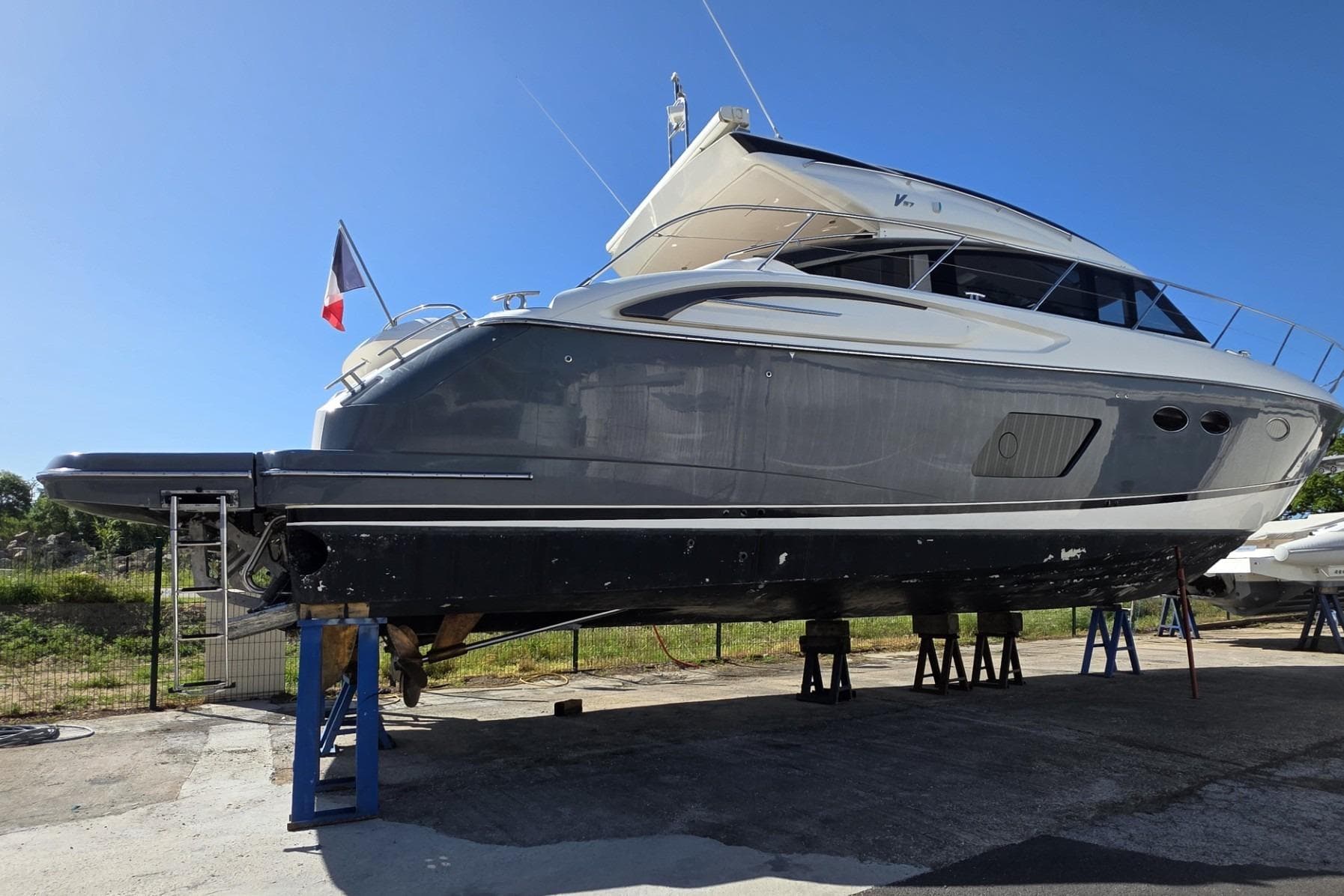 2012 Princess V57 yacht on stands, side view, with a flag, under clear blue sky.