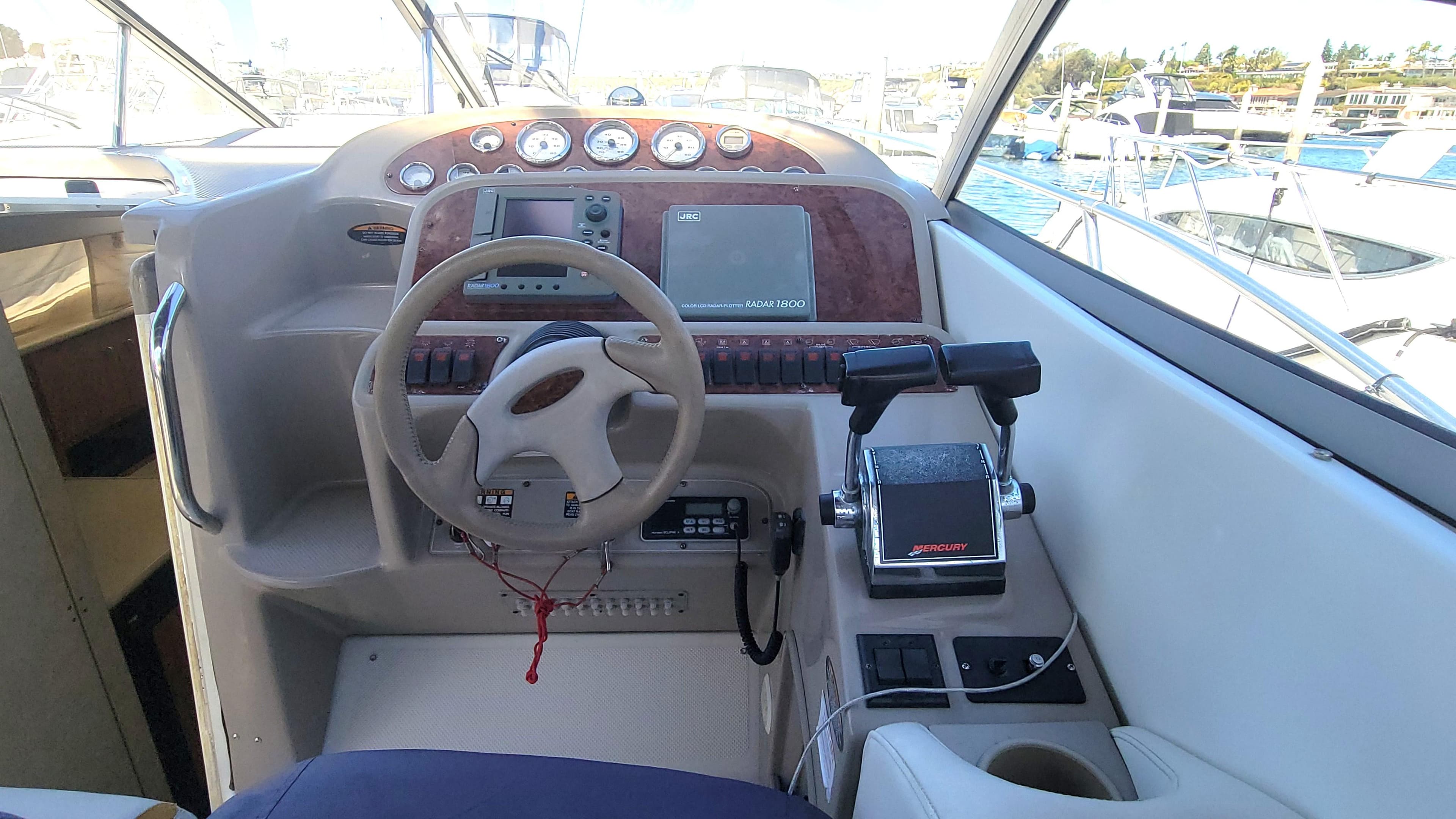 2001 Bayliner 3055 Ciera helm with steering wheel, controls, and gauges in a marina setting.