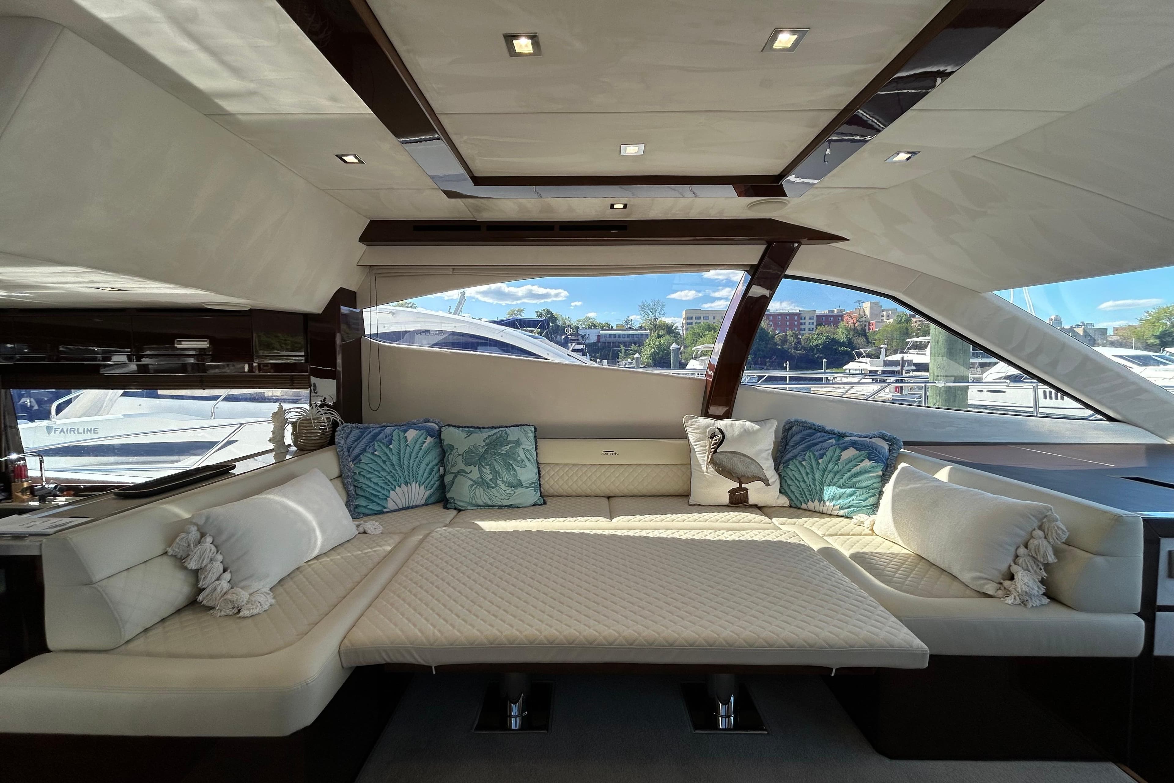 Luxurious interior of 2019 Galeon 550 Fly yacht with elegant seating and decorative pillows.