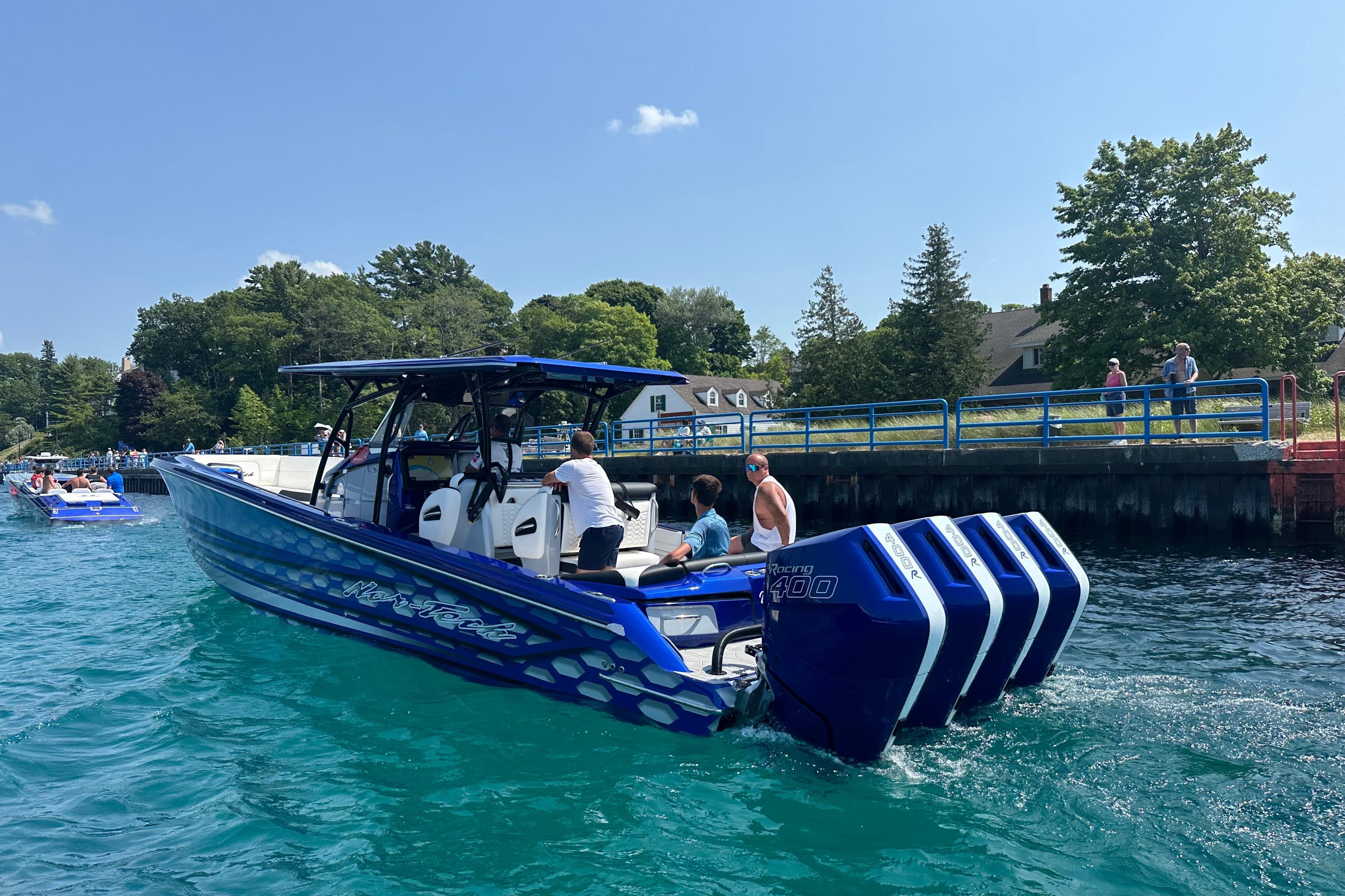 2025 Nor-Tech 390 Sport boat with quad engines on a sunny day near a dock.