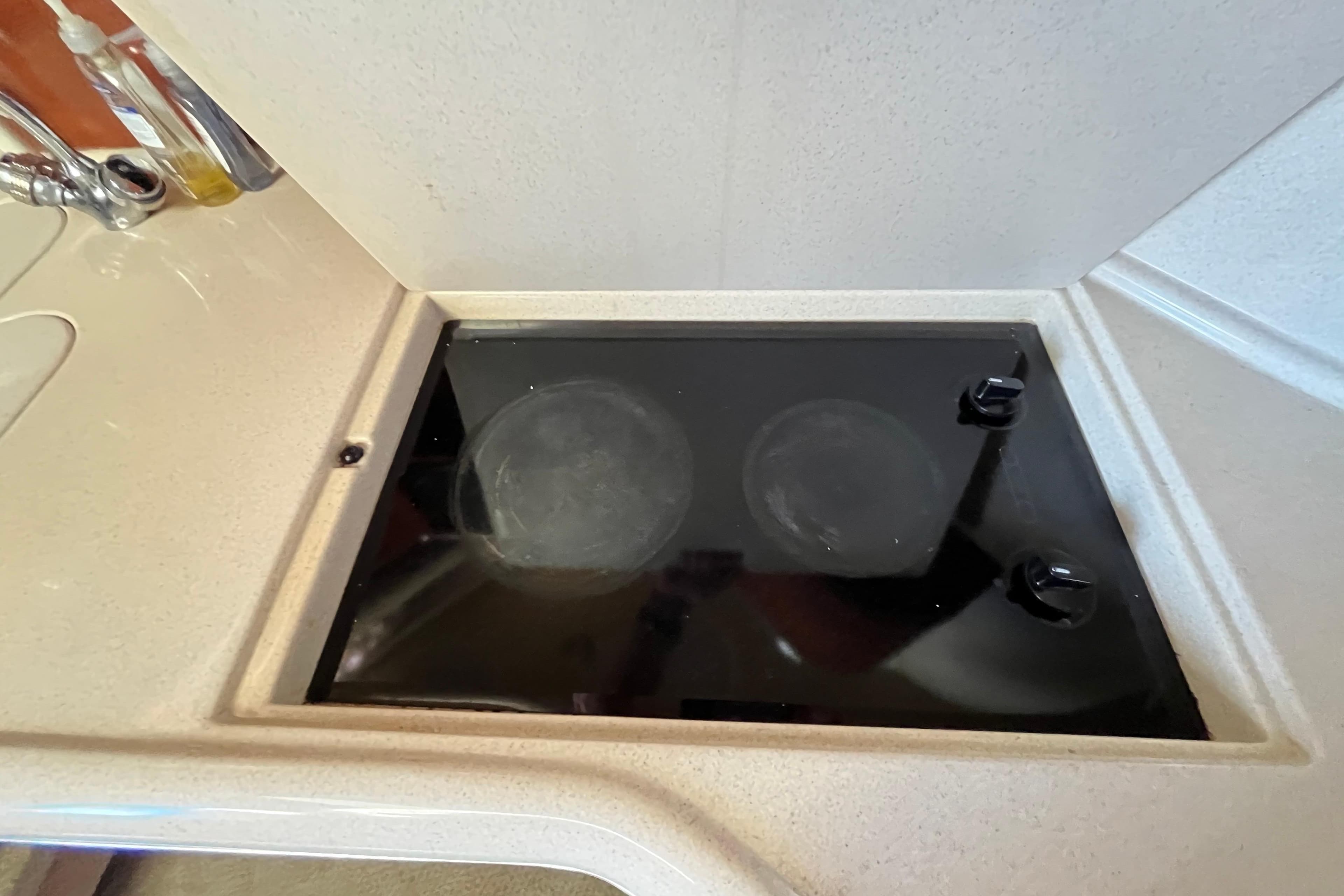 2003 Searay 380 yacht kitchen with a sleek black stovetop.