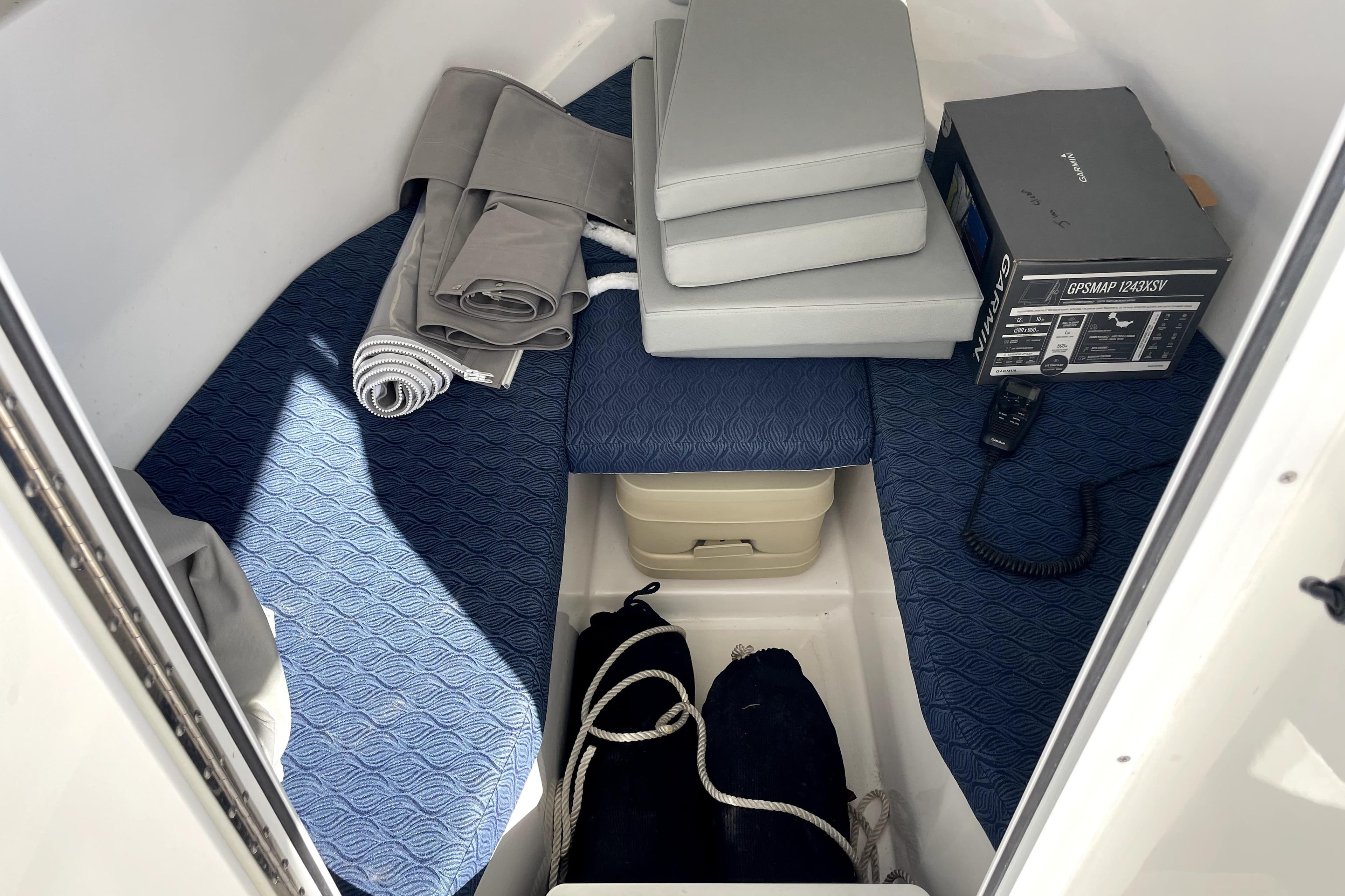 Interior cabin of 2024 NorthCoast 235 boat with cushions and GPS equipment.