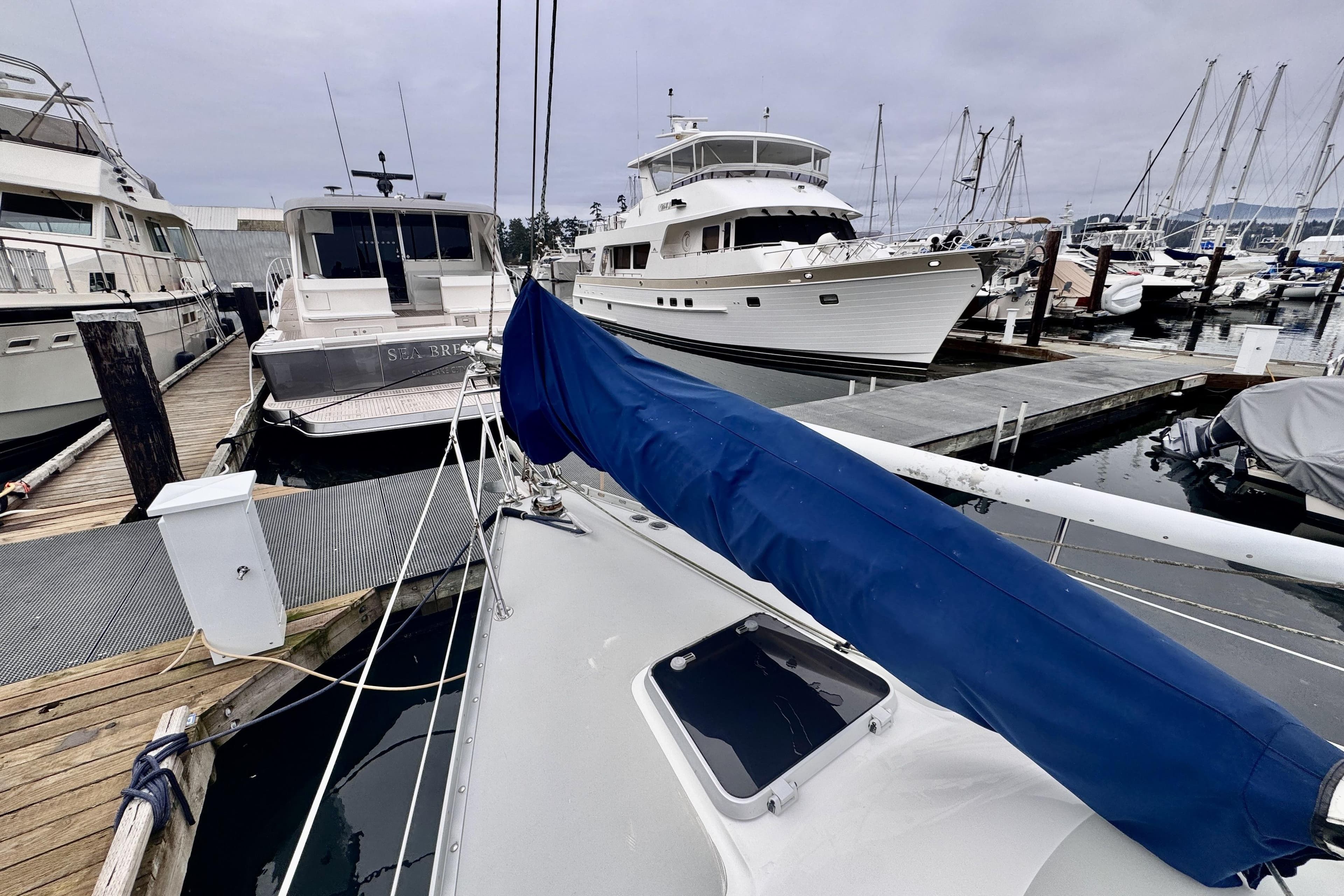 Sailboats docked at marina, featuring a 1991 Freedom 38 with blue sail cover.