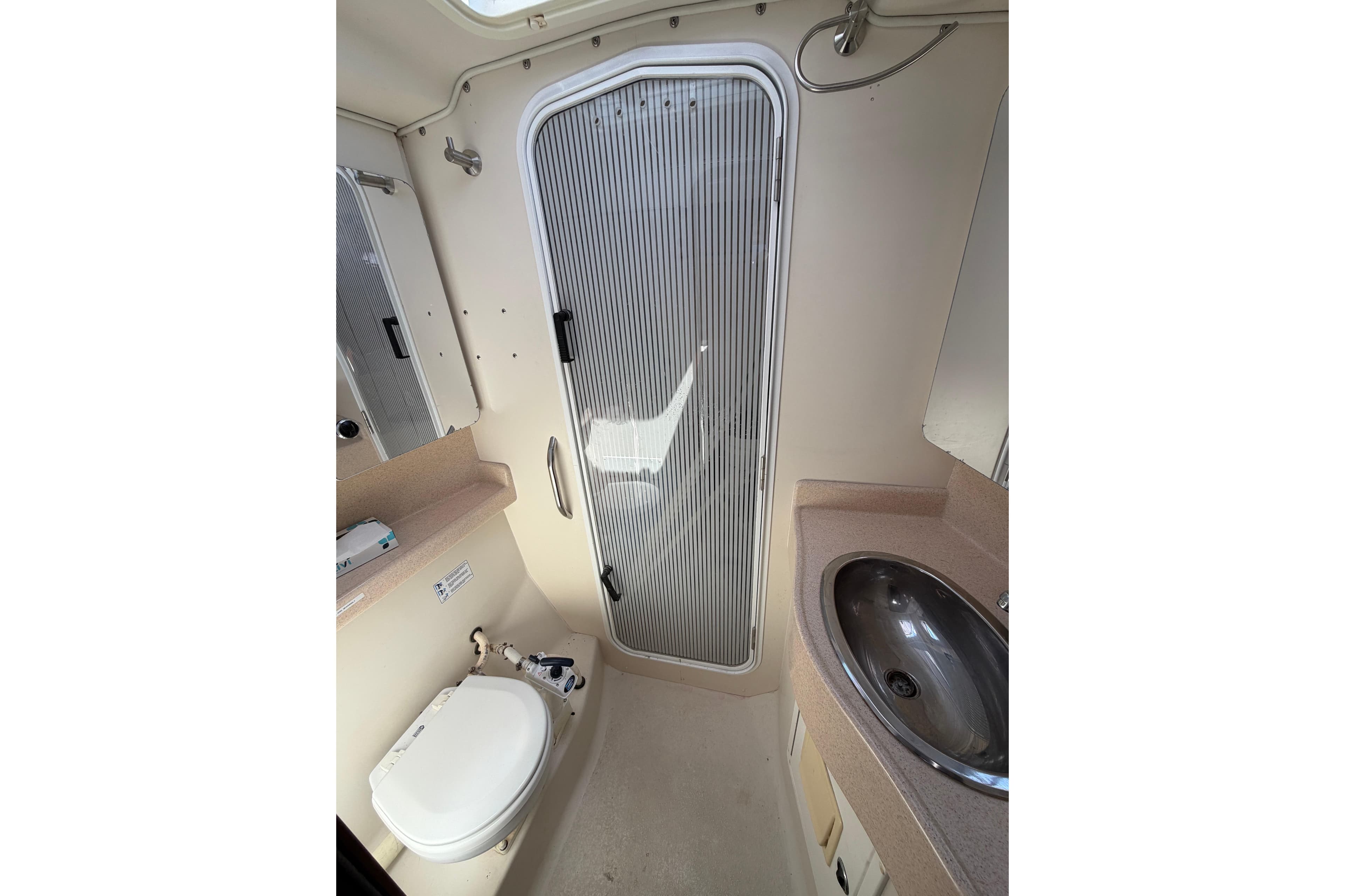 Bathroom interior of 2002 Catalina 470 yacht with toilet, sink, and shower door.