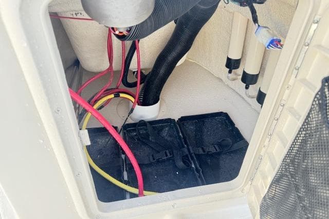 Battery compartment of 2026 Carolina Skiff 192 JLS with wiring and hoses visible.