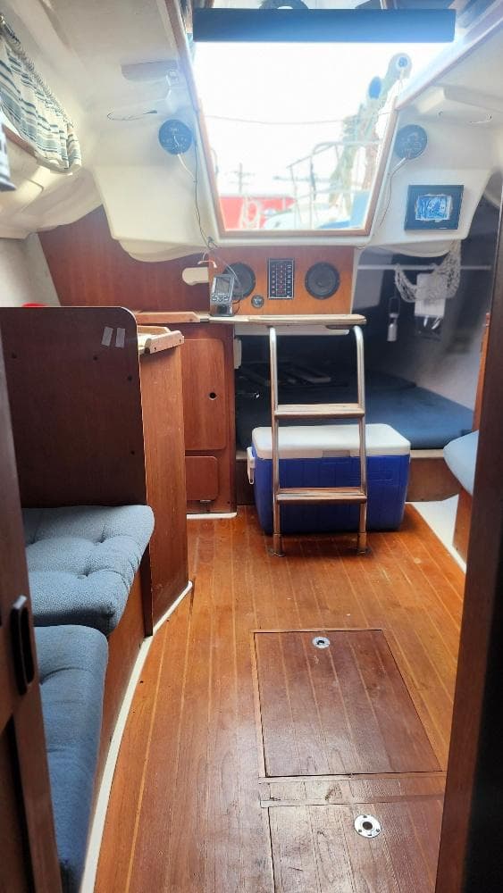 Interior of a 1987 Hunter 26.5 sailboat with wooden flooring and seating area.