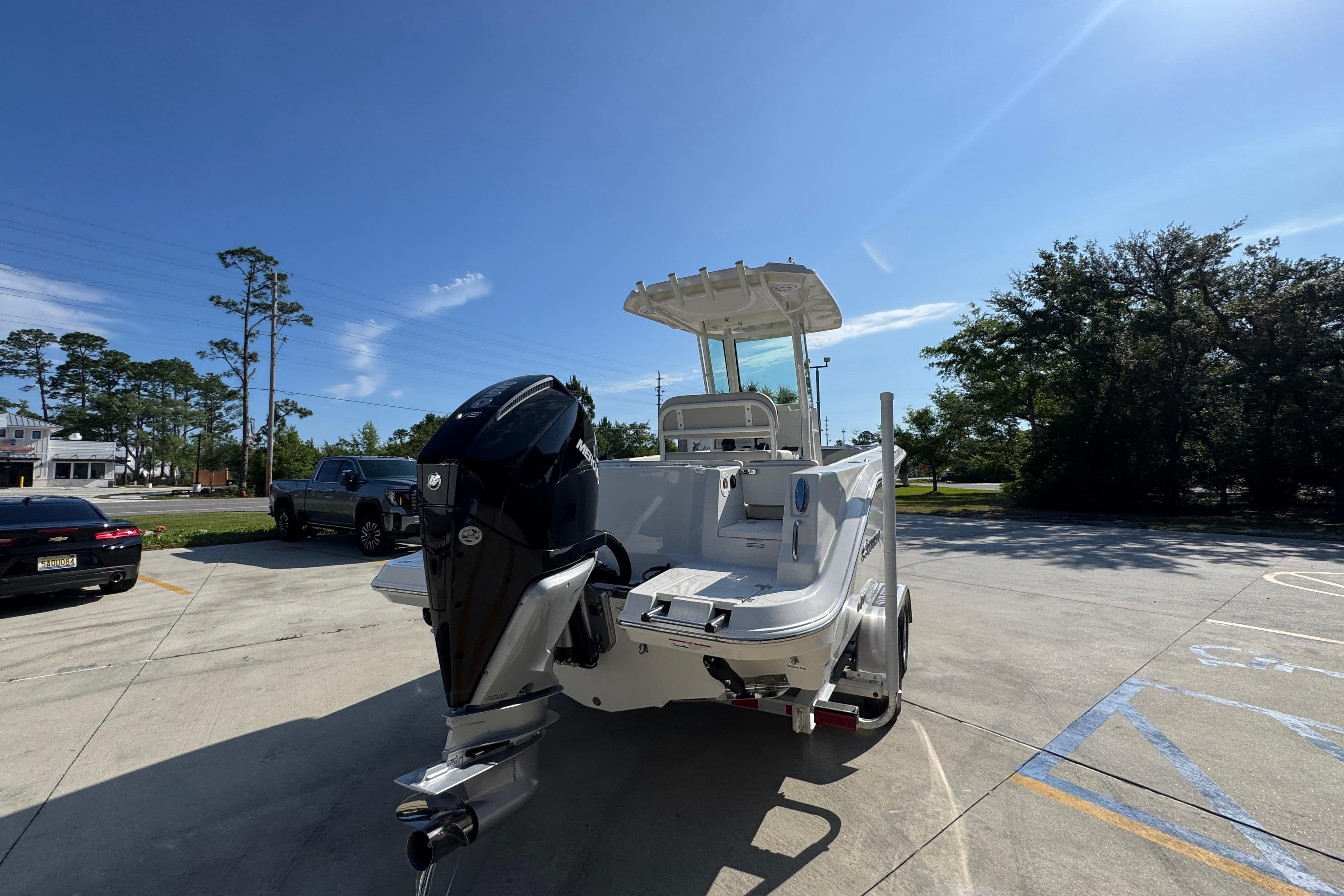 2026 Sailfish 232 CC boat with outboard motor in a sunny parking lot.