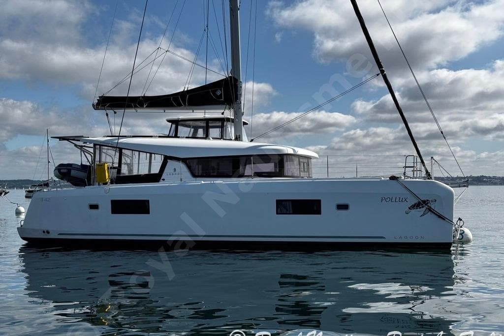 2018 Lagoon 42 catamaran on calm water under a partly cloudy sky.