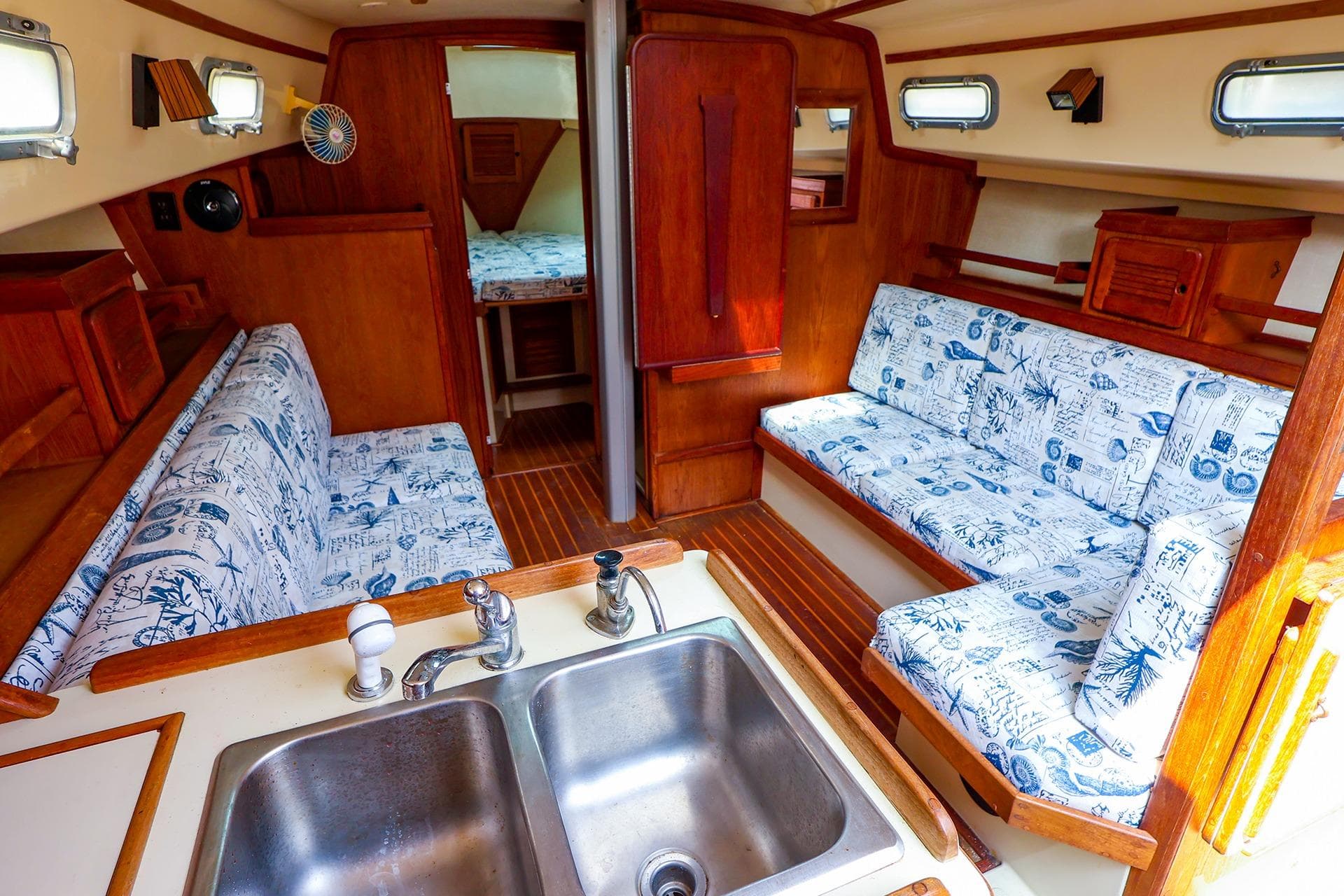 Interior of 1985 Island Packed 31 yacht with nautical-themed upholstery and wooden finishes.