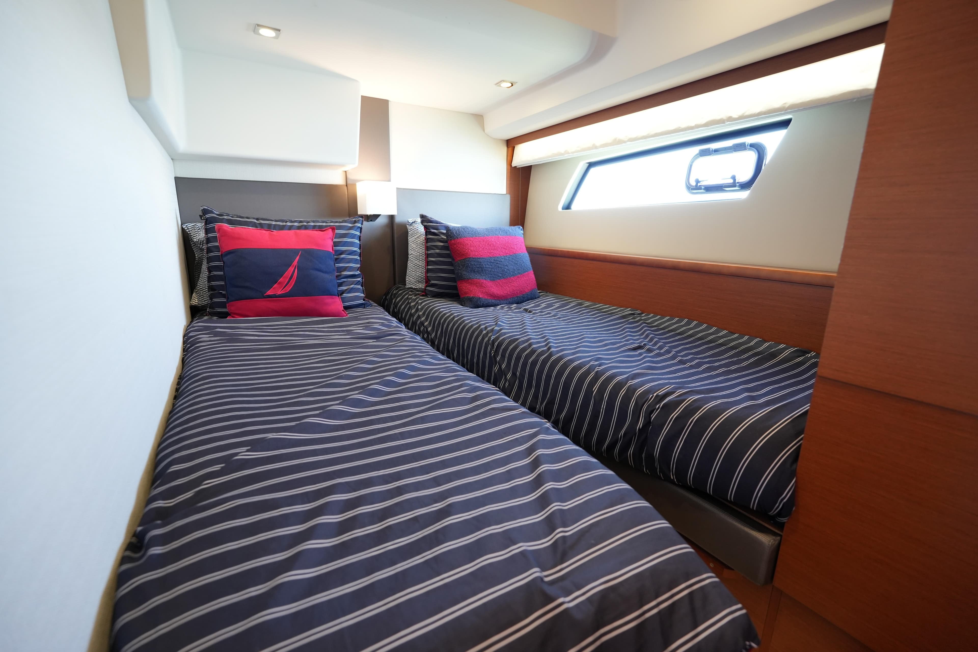 Twin beds in a 2015 Prestige 500S yacht cabin with striped bedding and nautical-themed pillows.