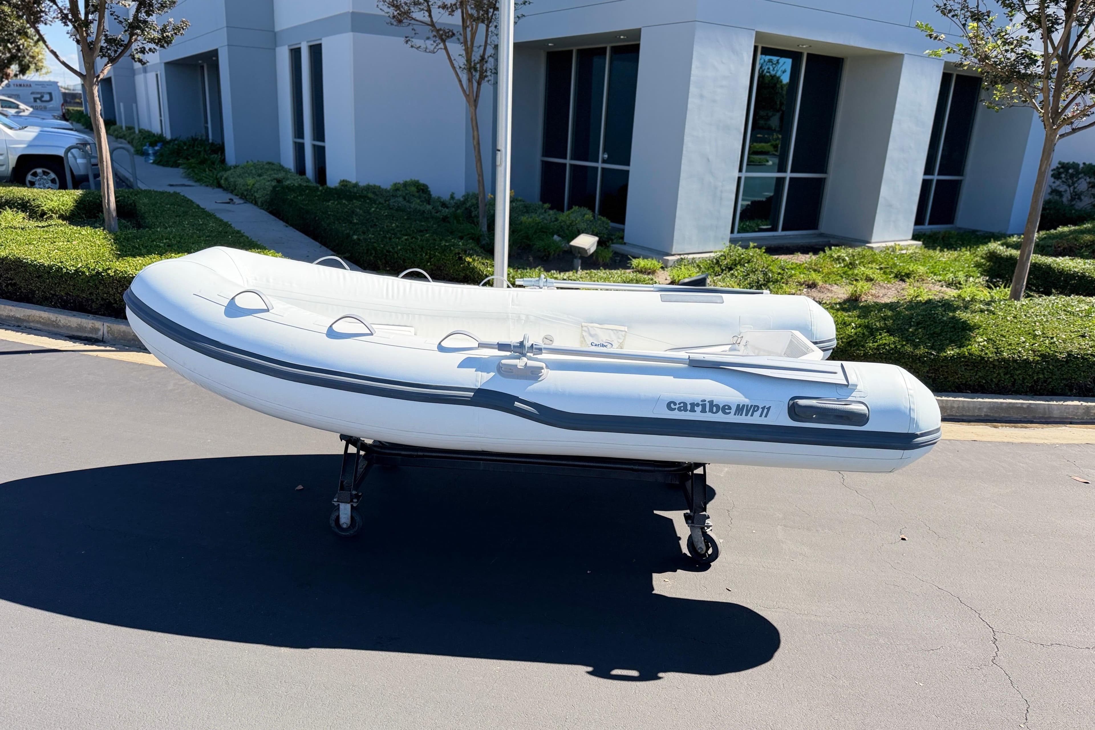 Inflatable Caribe MVP11 boat, 2025 model, displayed outdoors on a wheeled stand.