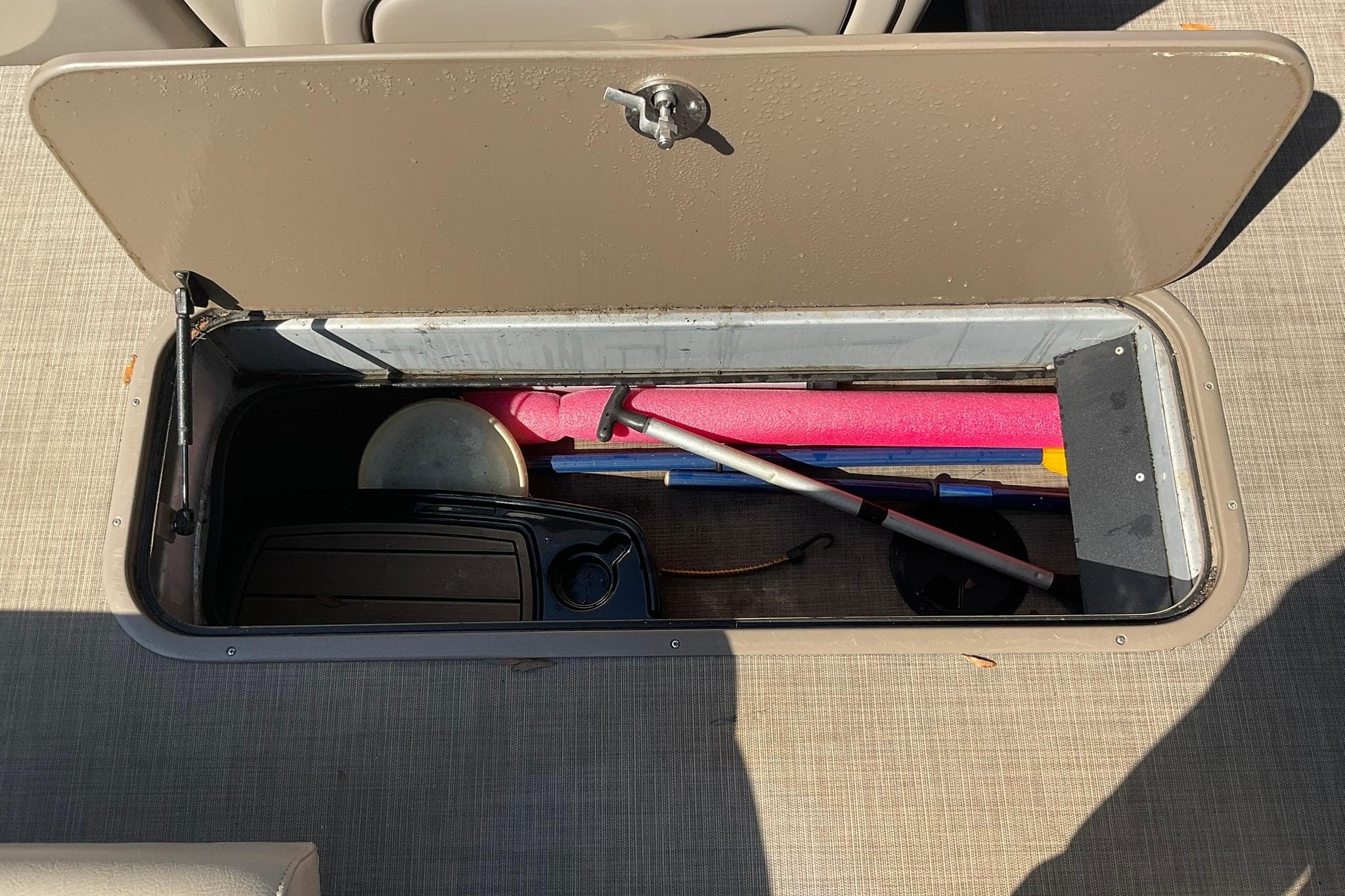 Storage compartment on a 2020 Sun Tracker Party Barge 22 XP3 with boating accessories.