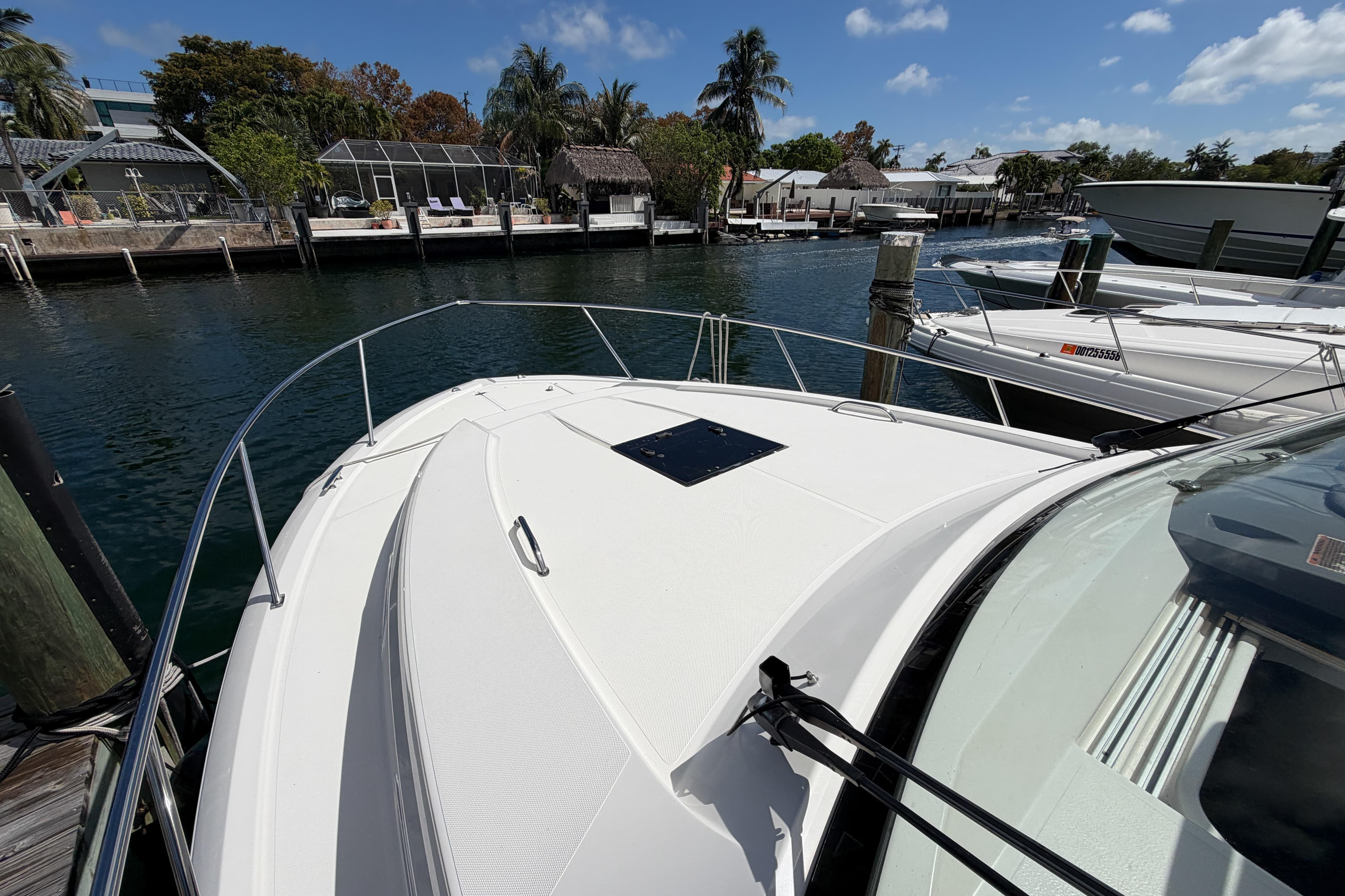 2018 Pursuit OS 355 Offshore boat docked in a scenic marina with palm trees.