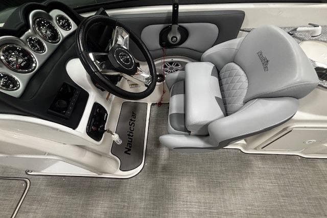 2023 NauticStar 243DC Sport Deck interior with steering wheel and cushioned captain's chair.