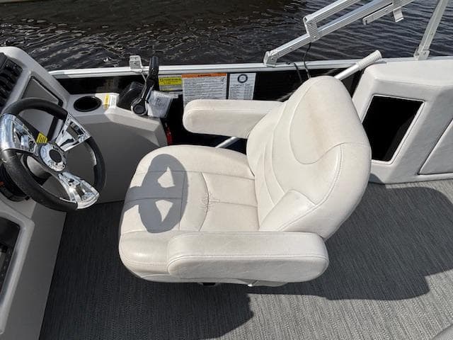 Captain's chair on 2022 Sweetwater 2286 boat, featuring a sleek steering wheel and control panel.
