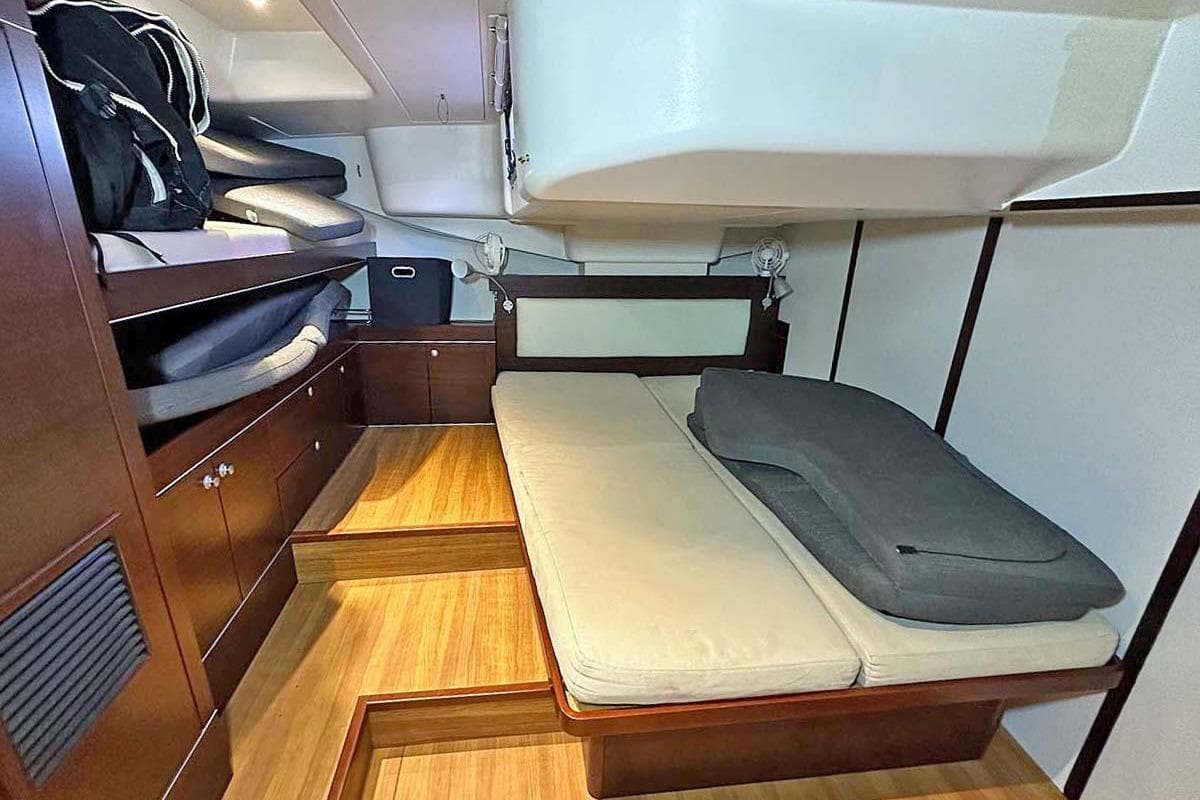 Interior cabin of 2010 Hanse 545 yacht with wooden flooring and cozy bedding.