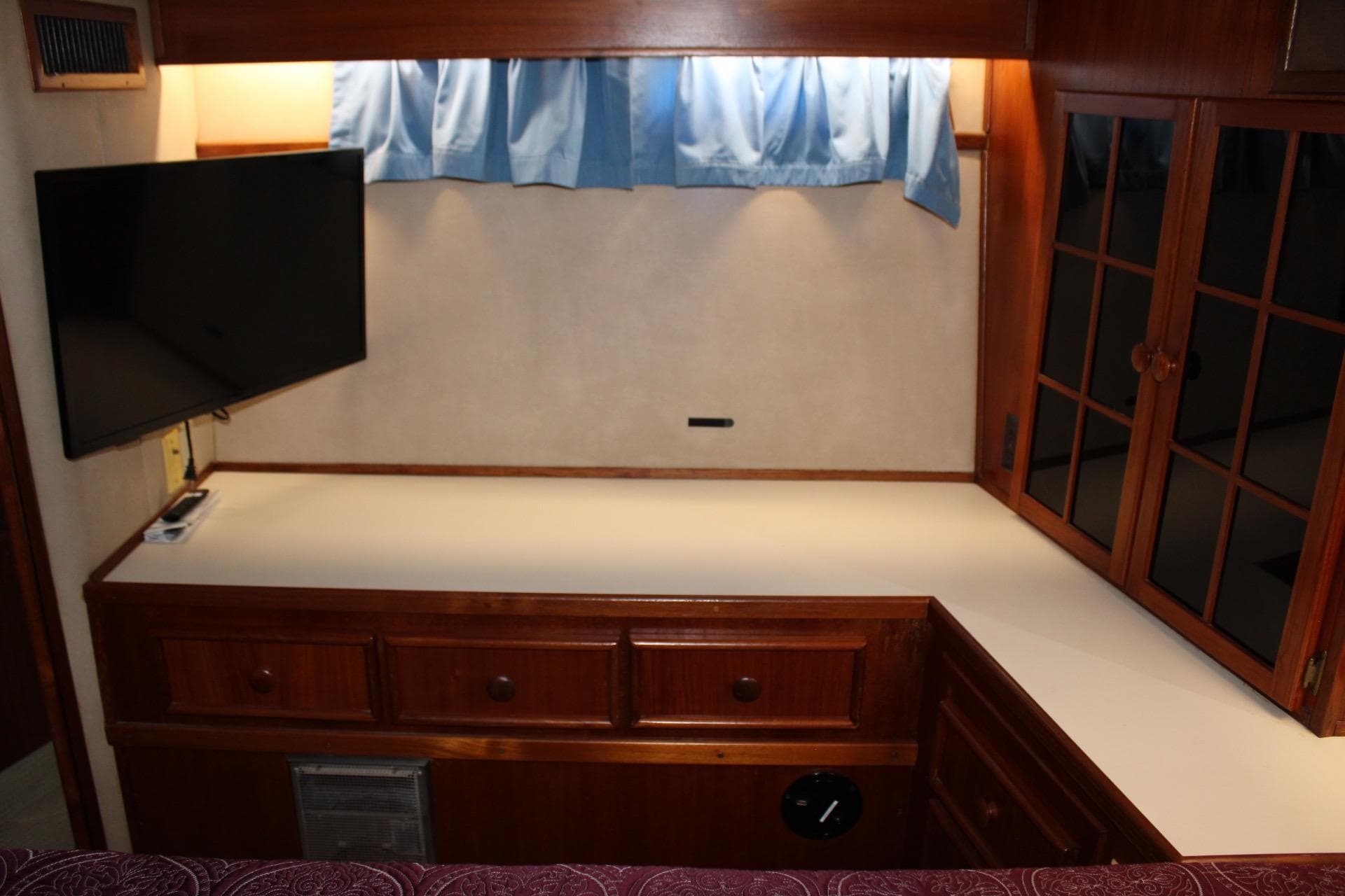 Interior of 1988 Chris Craft Constellation with TV, wooden cabinets, and blue curtains.