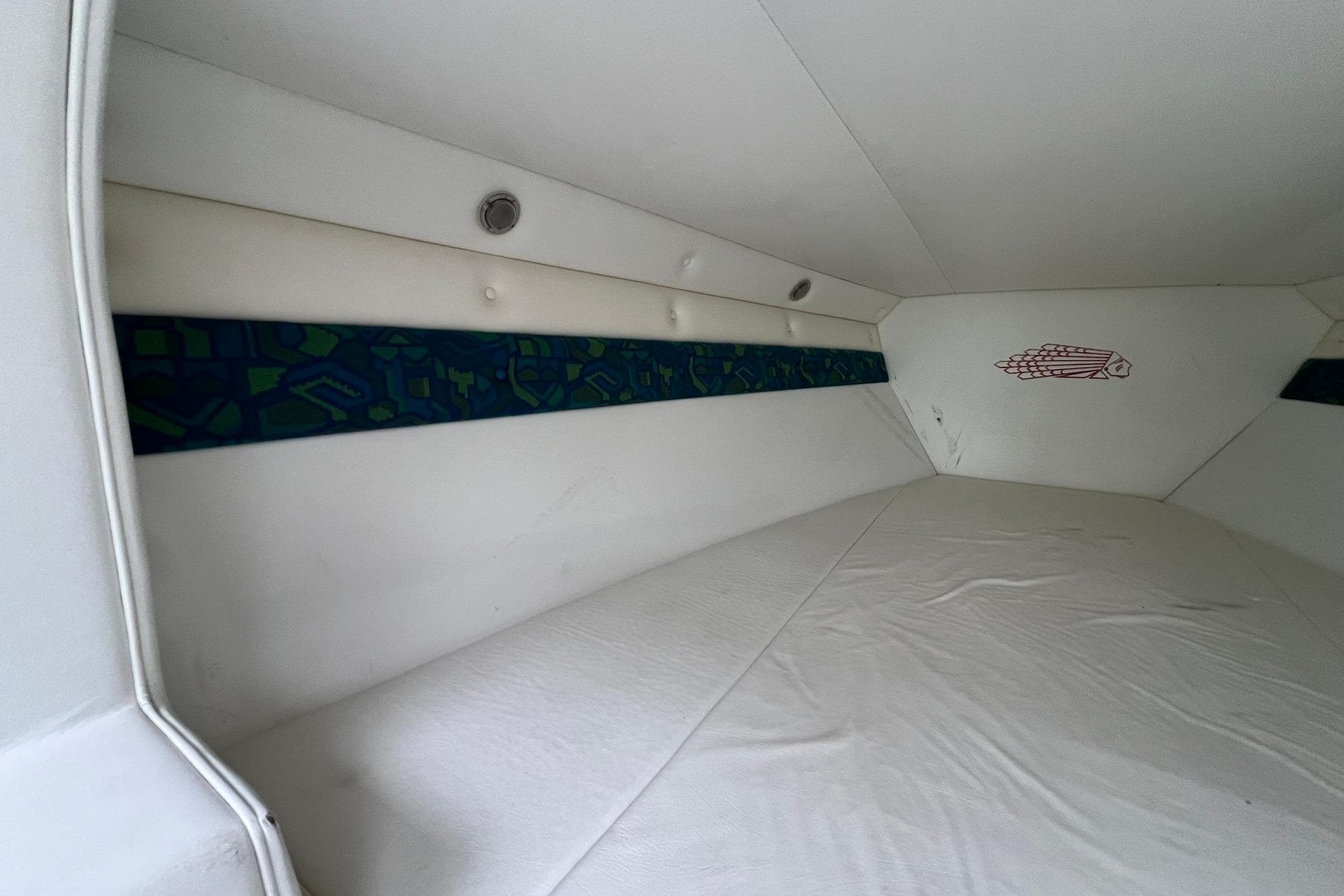 Interior cabin of a 1997 Apache Warrior boat, featuring white upholstery and geometric accents.
