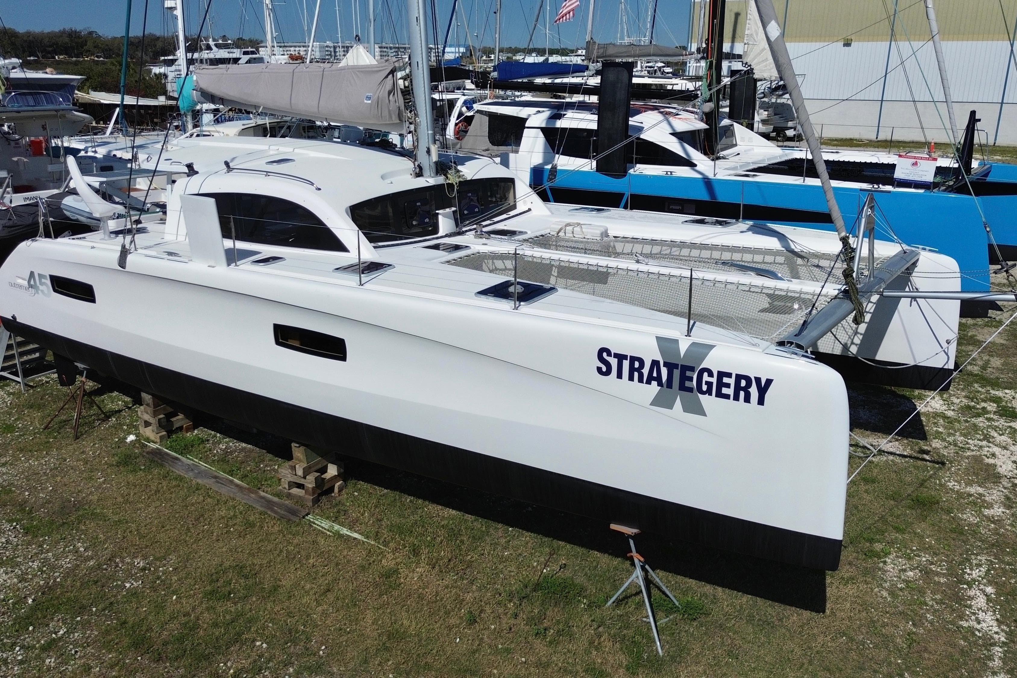 2014 Outremer 45 catamaran "Strategery" on land, surrounded by other boats.