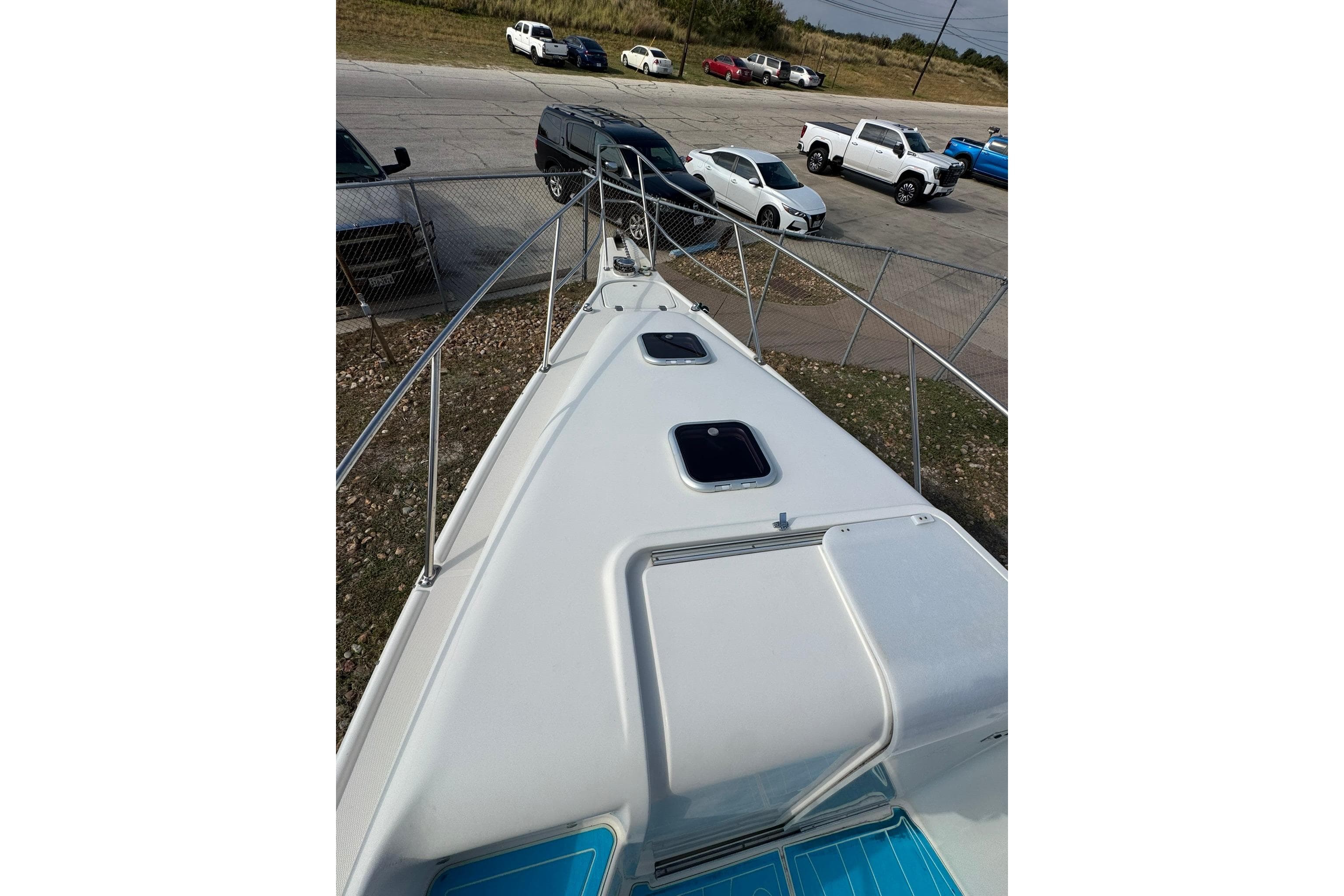 1996 Pro-Line 3400 Cuddy boat deck view with parked cars in the background.