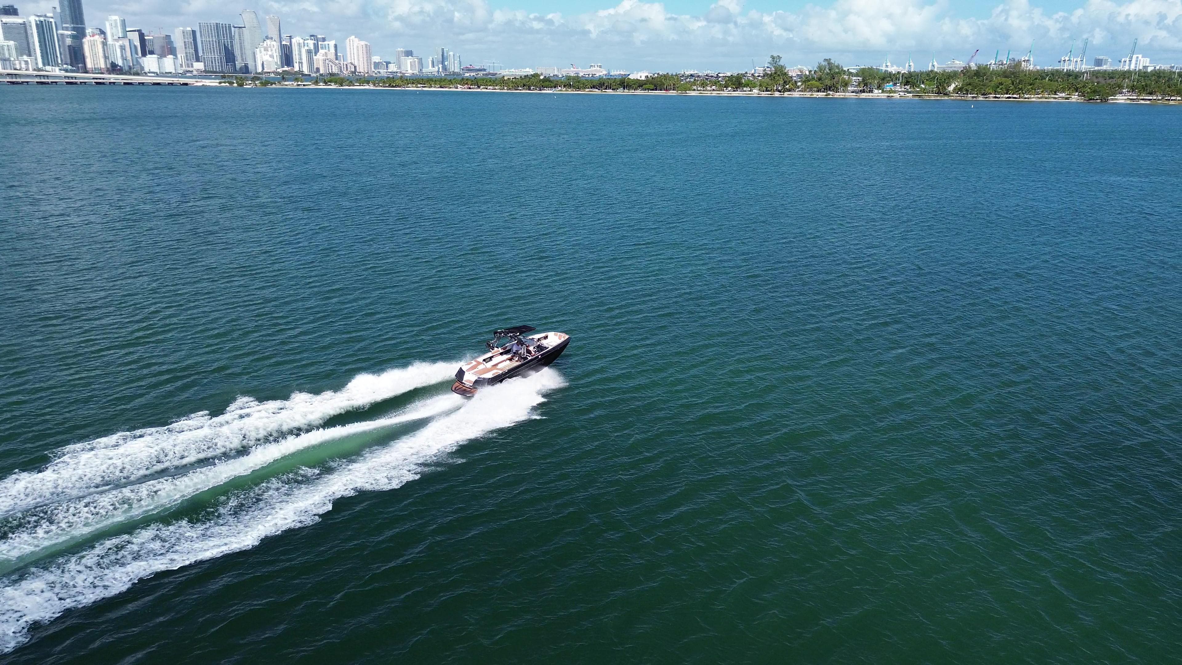 2018 Nautique Super Air Nautique G25 cruising on open water with city skyline in background.