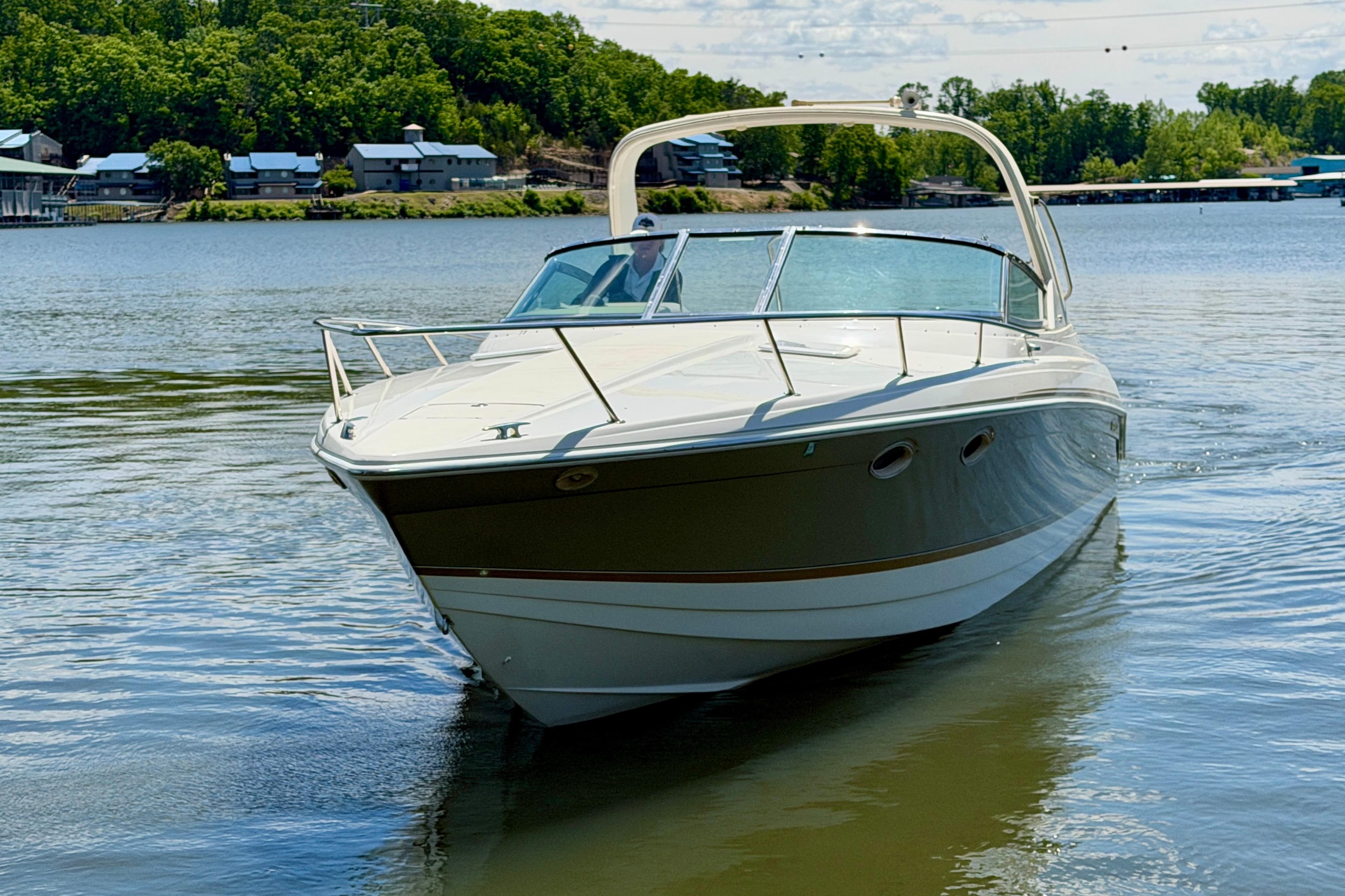 2003 Formula 330 Sun Sport boat cruising on a serene lake with lush green shoreline.