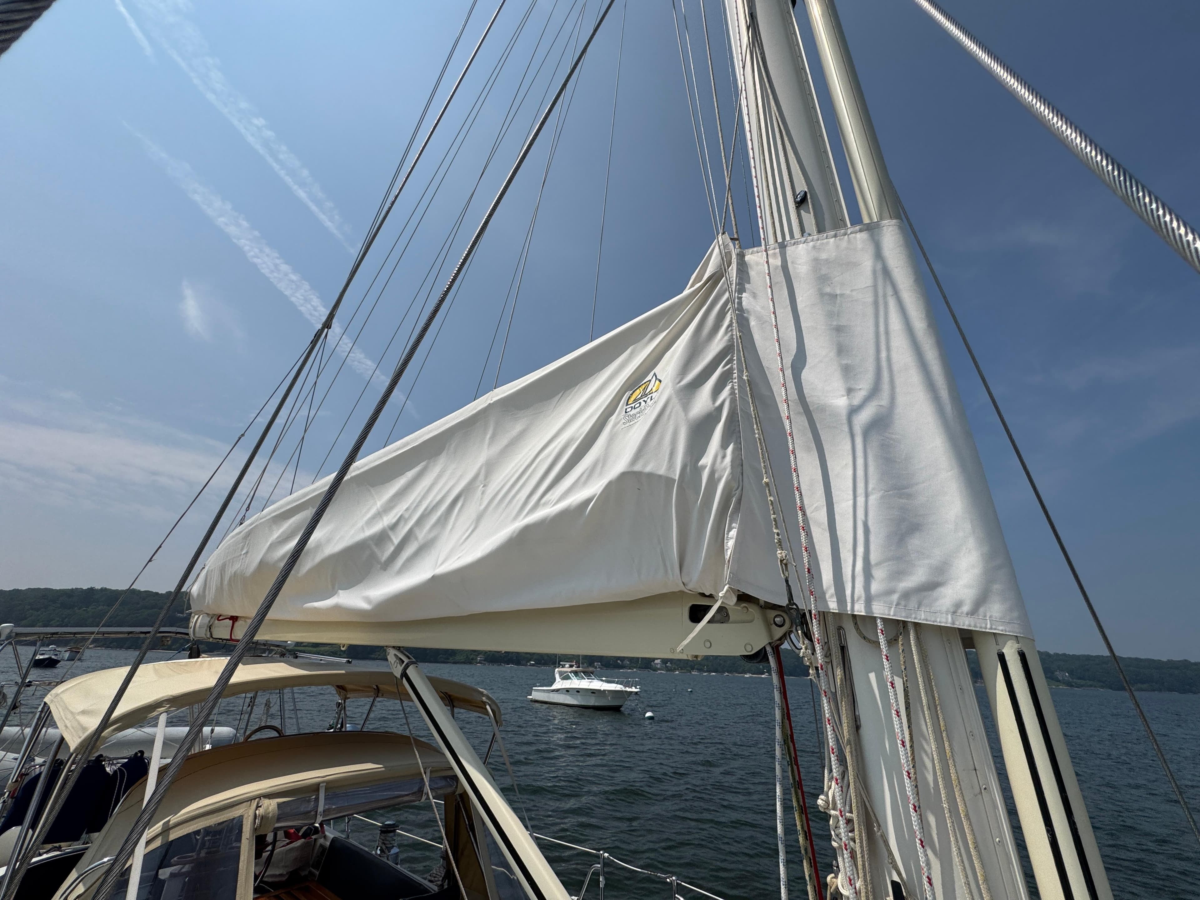 Sailboat mast and sail cover on a 1998 Hylas 46, anchored in a scenic bay.