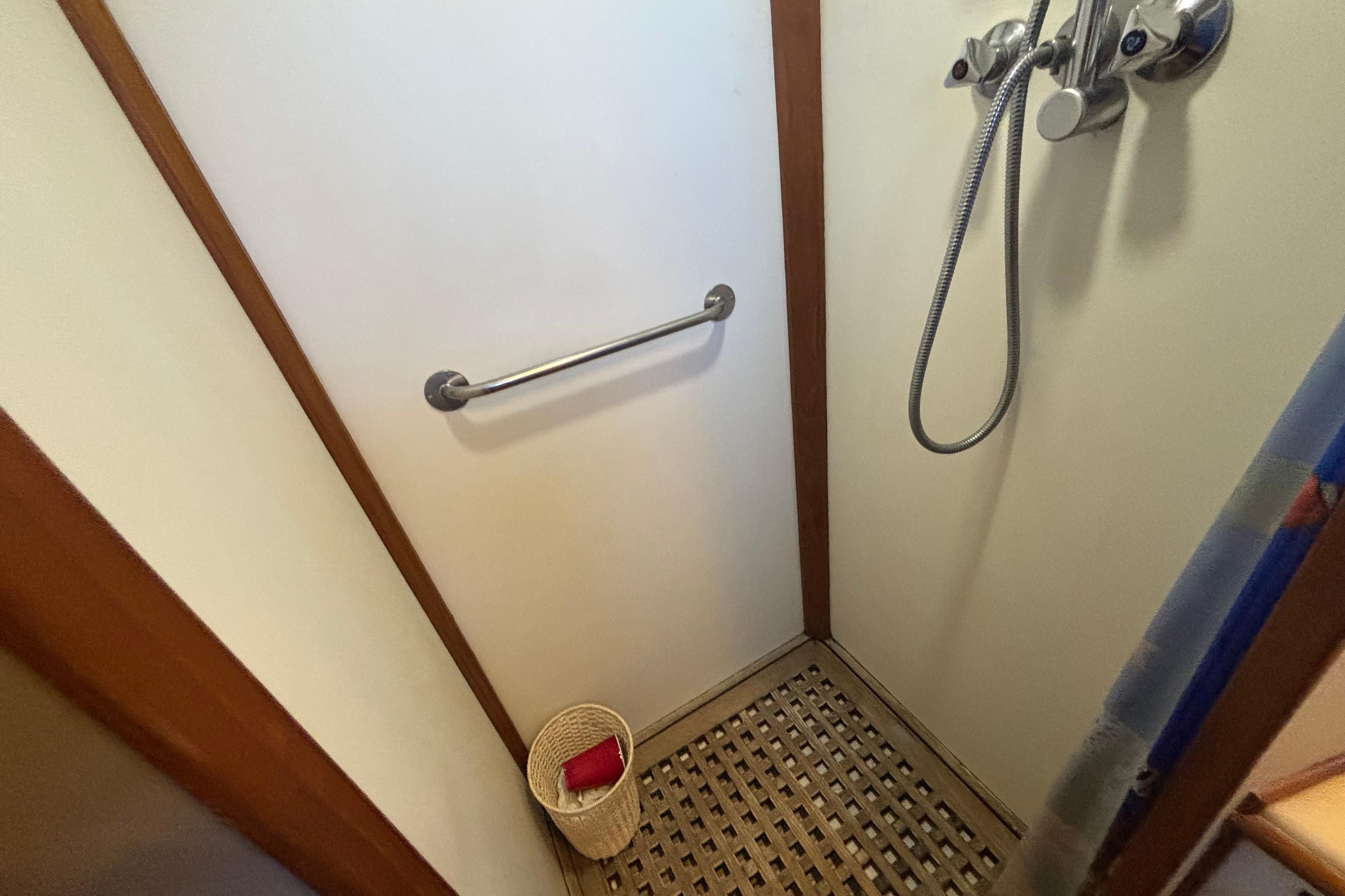 Shower area in 1989 Grand Banks 46 Classic yacht with handheld showerhead and wooden floor.