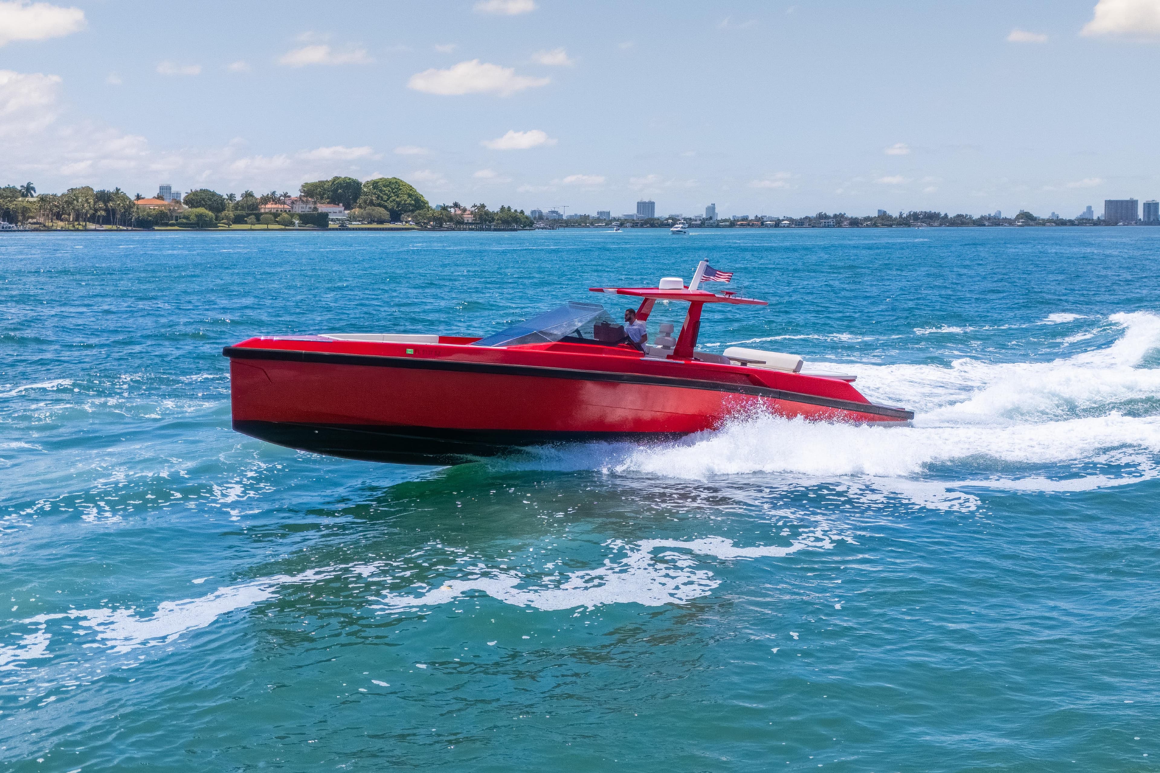 Red 2021 Wally 48 yacht cruising on blue ocean waters under a clear sky.