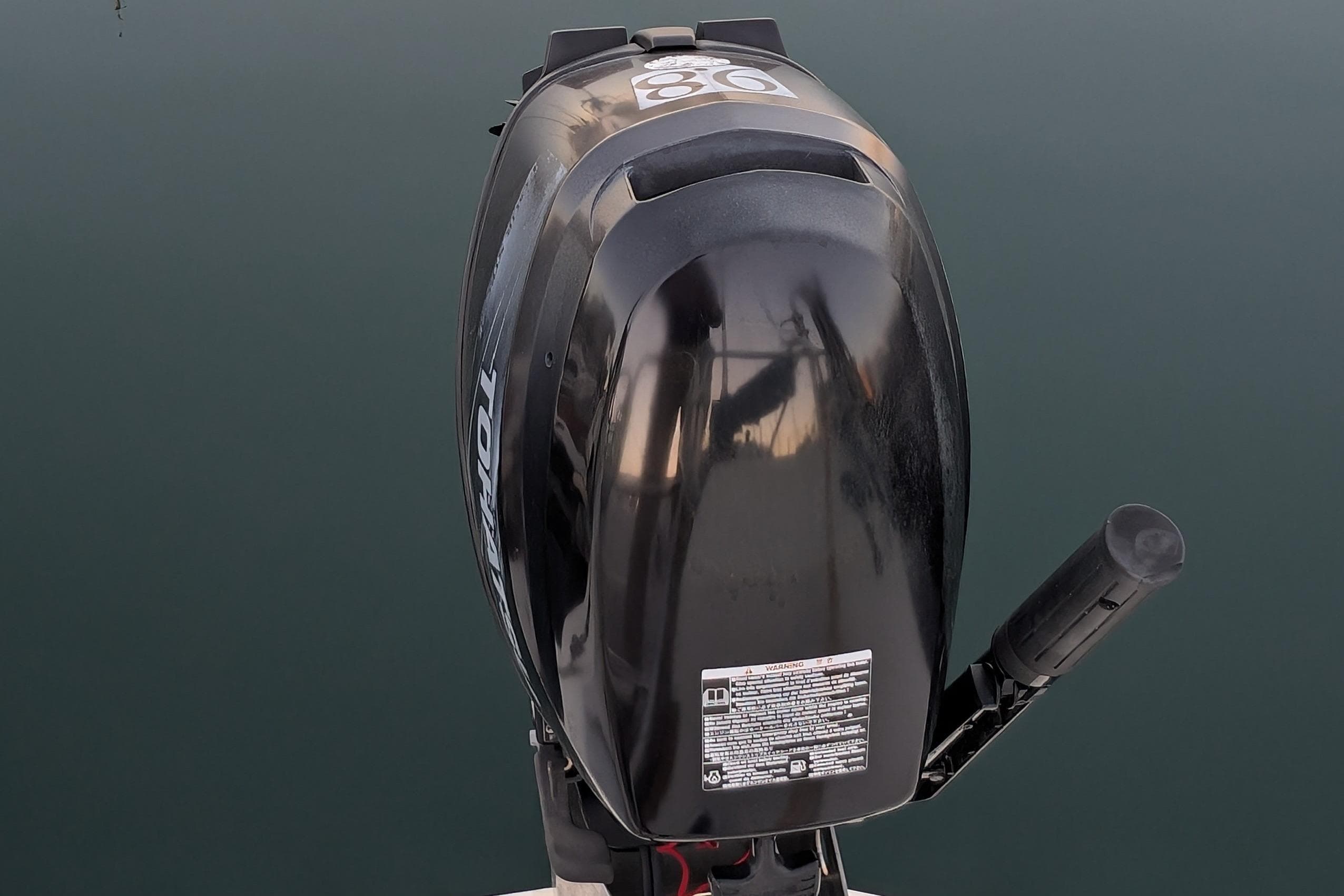 Outboard motor on a 1990 Catalina Capri 26 sailboat, reflecting on calm water.