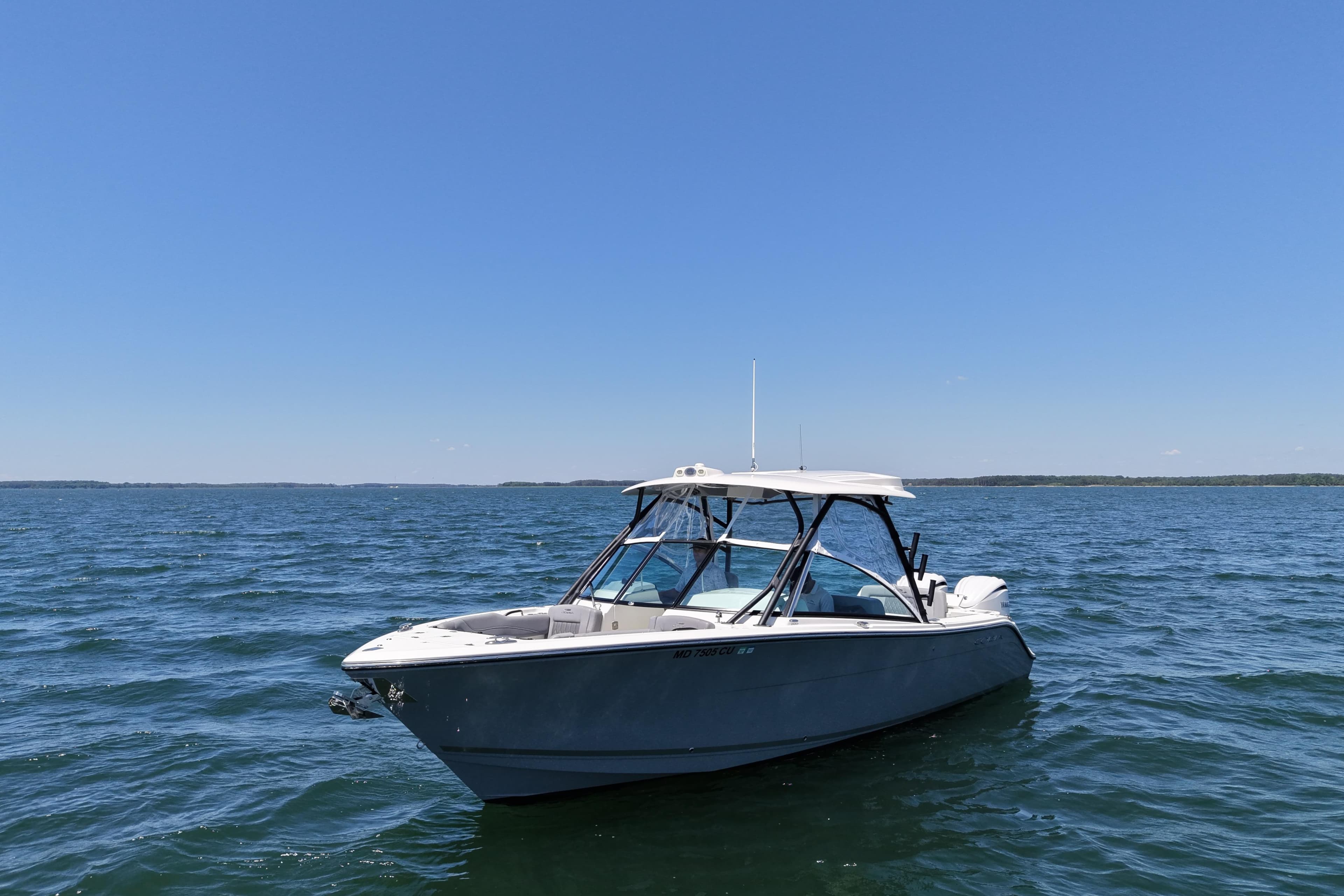 2024 Cobia 280 Dual Console boat on open water under clear blue sky.