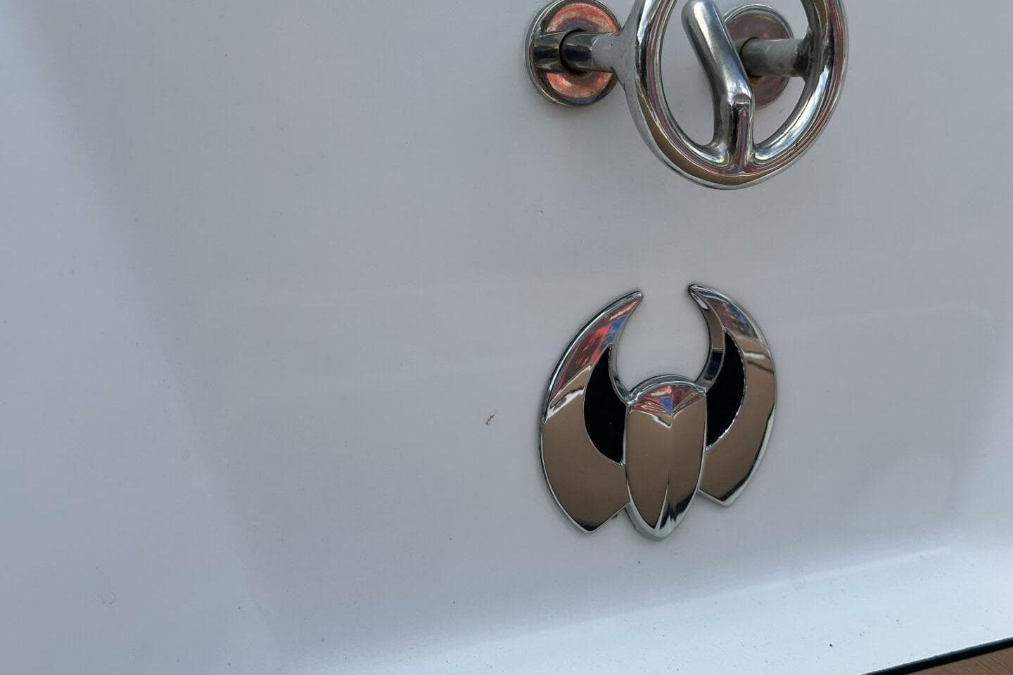 2021 Scarab 215 boat emblem and chrome hardware on white surface.