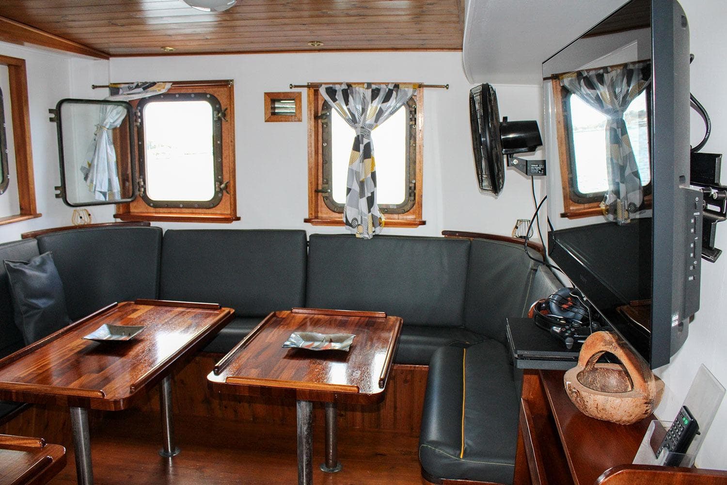 Interior of 1970 Custom CD Holmes Clovelly Class Tender, featuring cozy seating and wooden tables.