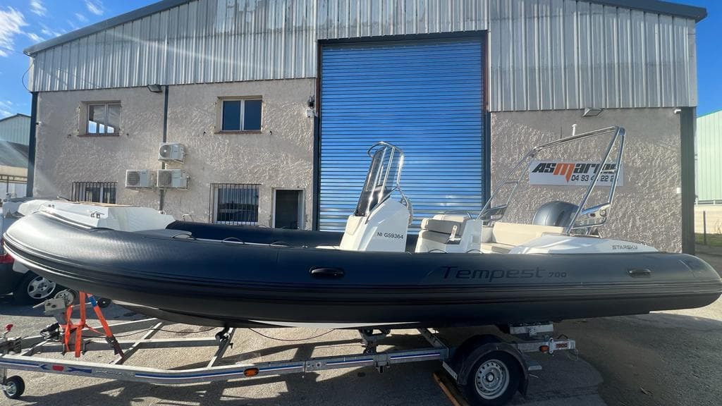 2023 Capelli Tempest 700 boat on trailer, parked outside industrial building.