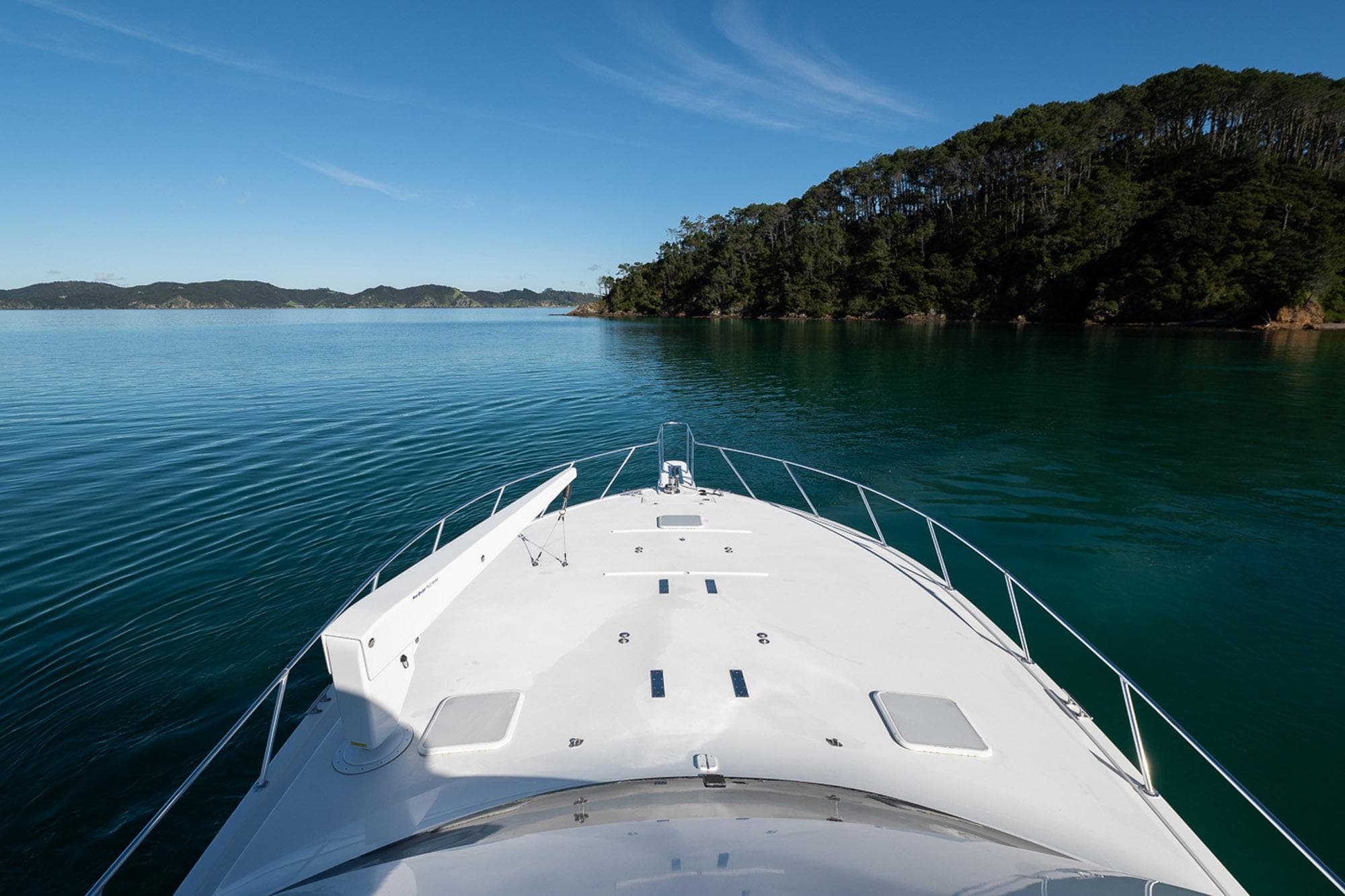 Bow view of 2003 Viking 48 Convertible yacht cruising near lush island.