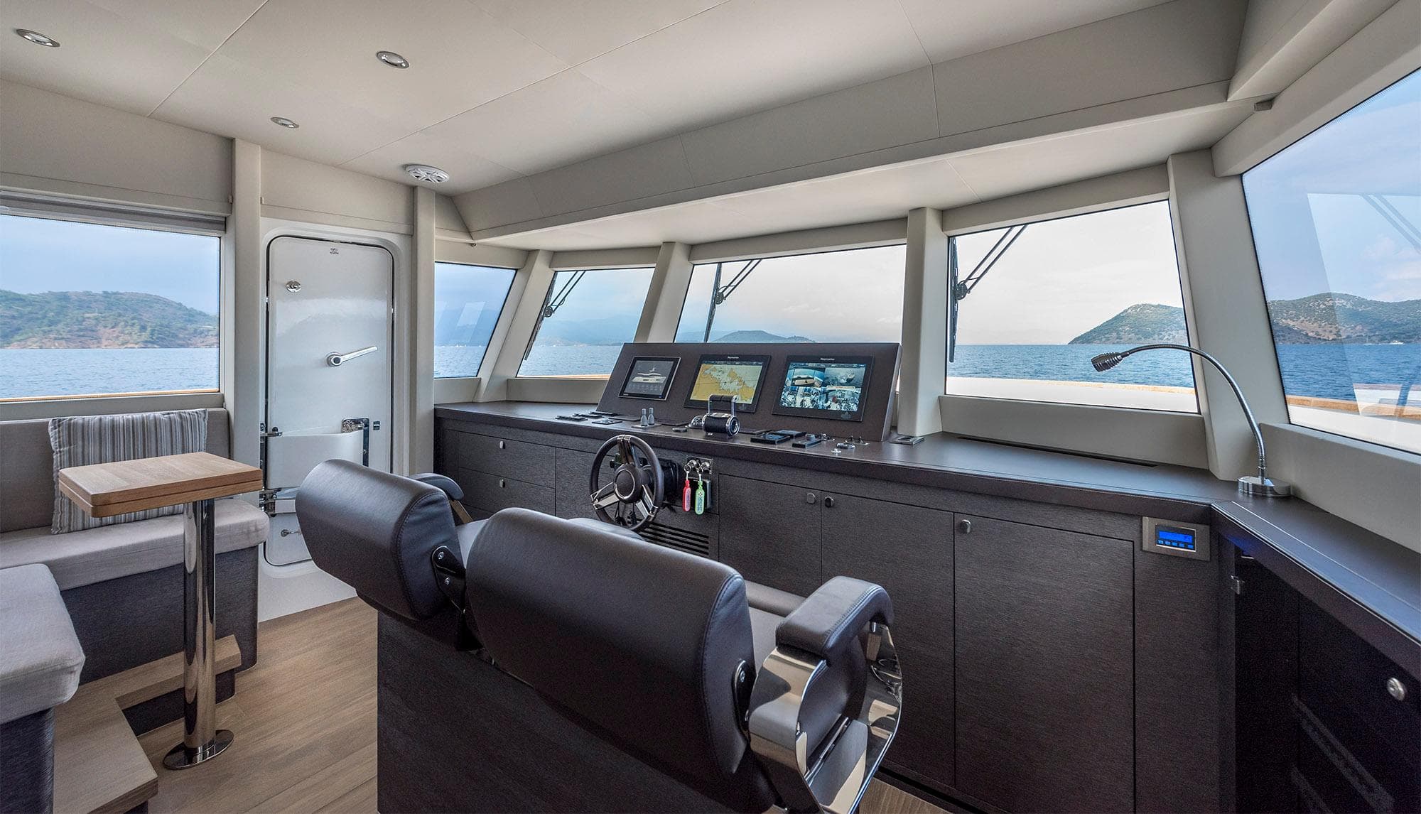 2025 Numarine 26XP yacht interior with modern helm, panoramic windows, and seating area.