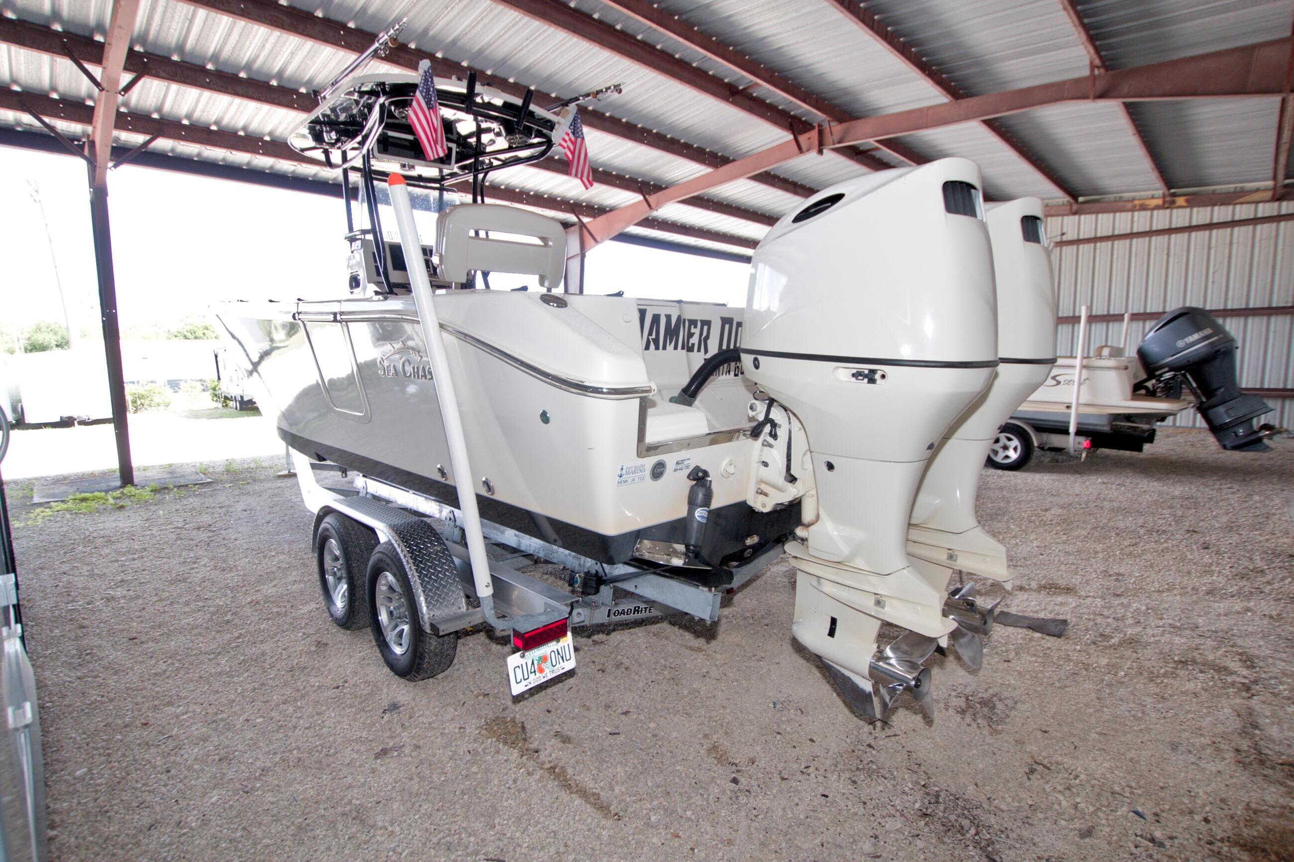 2018 Sea Chaser 27 HFC CC boat with dual engines on trailer in covered storage.