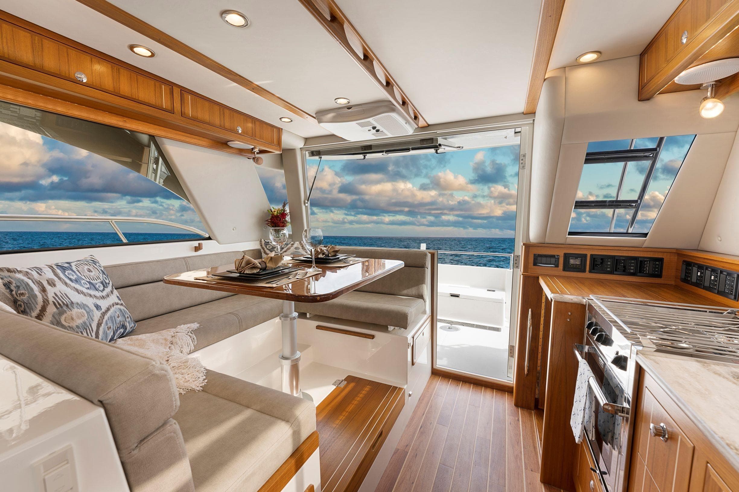 Luxurious interior of 2026 Aspen C128 Flybridge yacht with ocean view and elegant dining area.