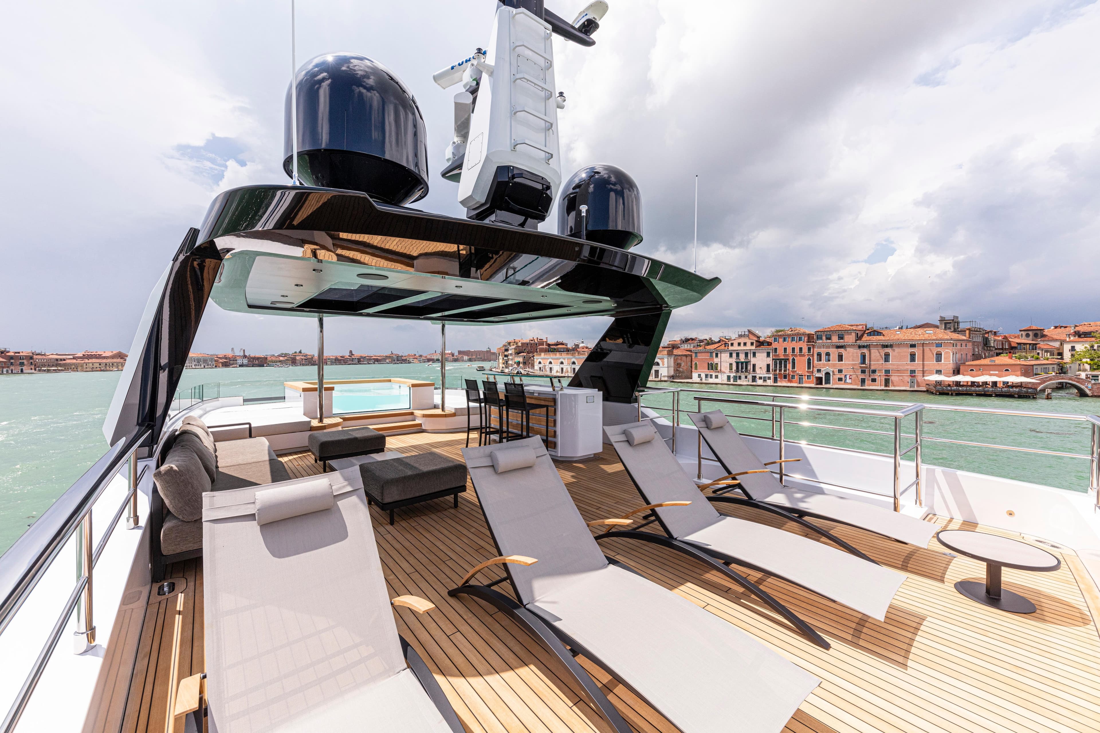 Luxurious Ocean King Ducale 120 yacht deck with sun loungers, overlooking scenic waterfront, 2027 model.