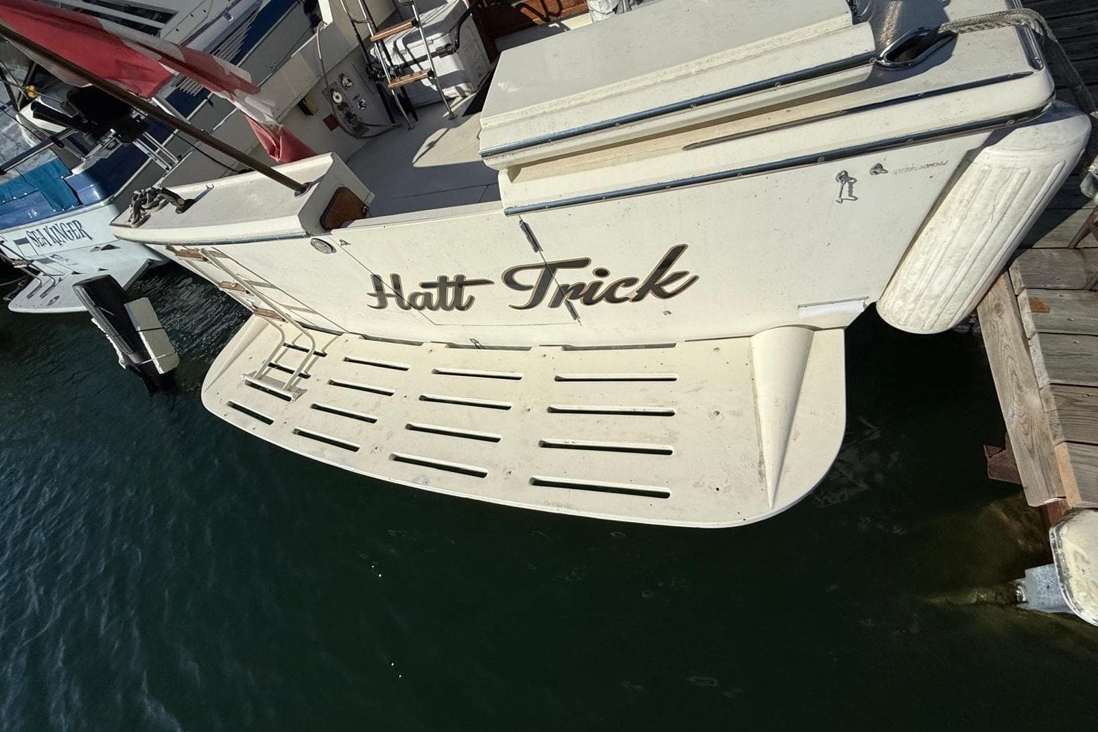1984 Hatteras 36 Convertible boat named "Hatt Trick" docked at a marina.
