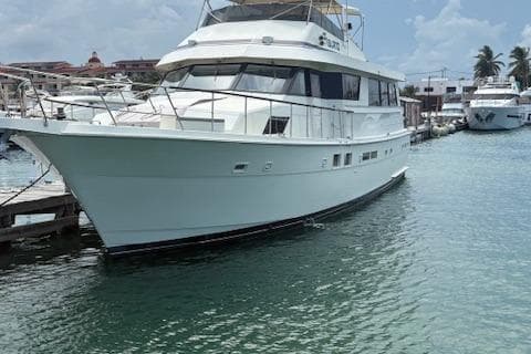 1988 Hatteras 70 yacht docked in a marina with clear blue water.