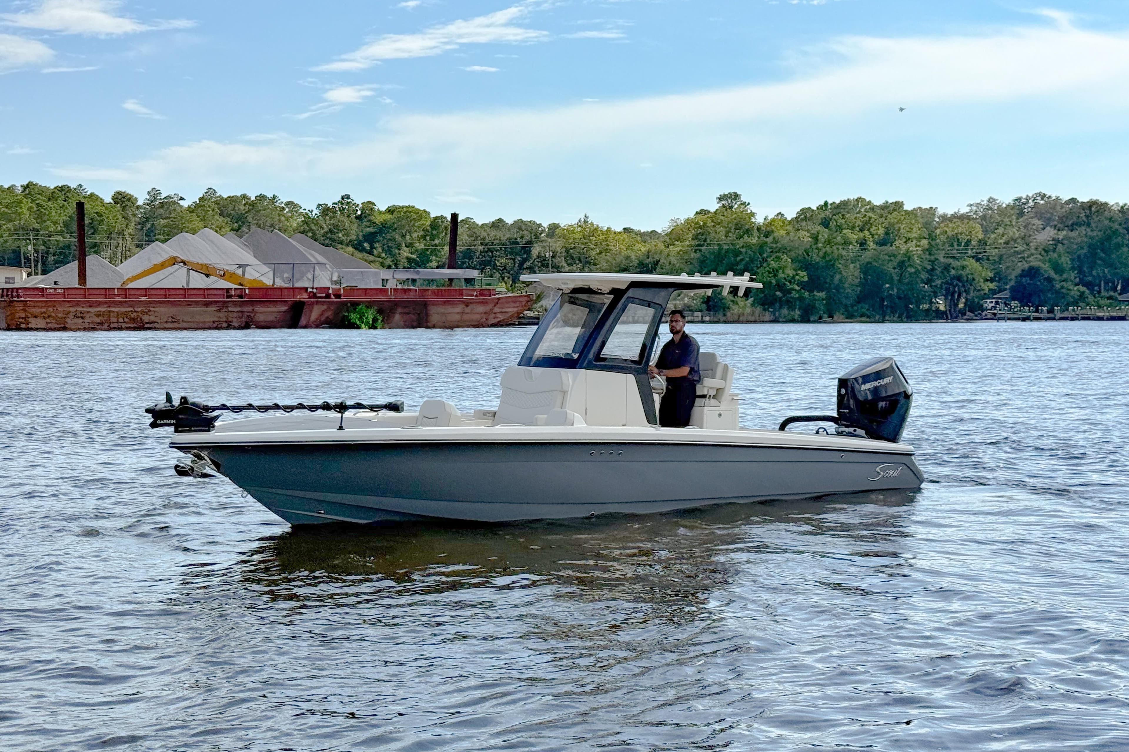 2026 Scout 281 XSS boat on a calm river with trees in the background.