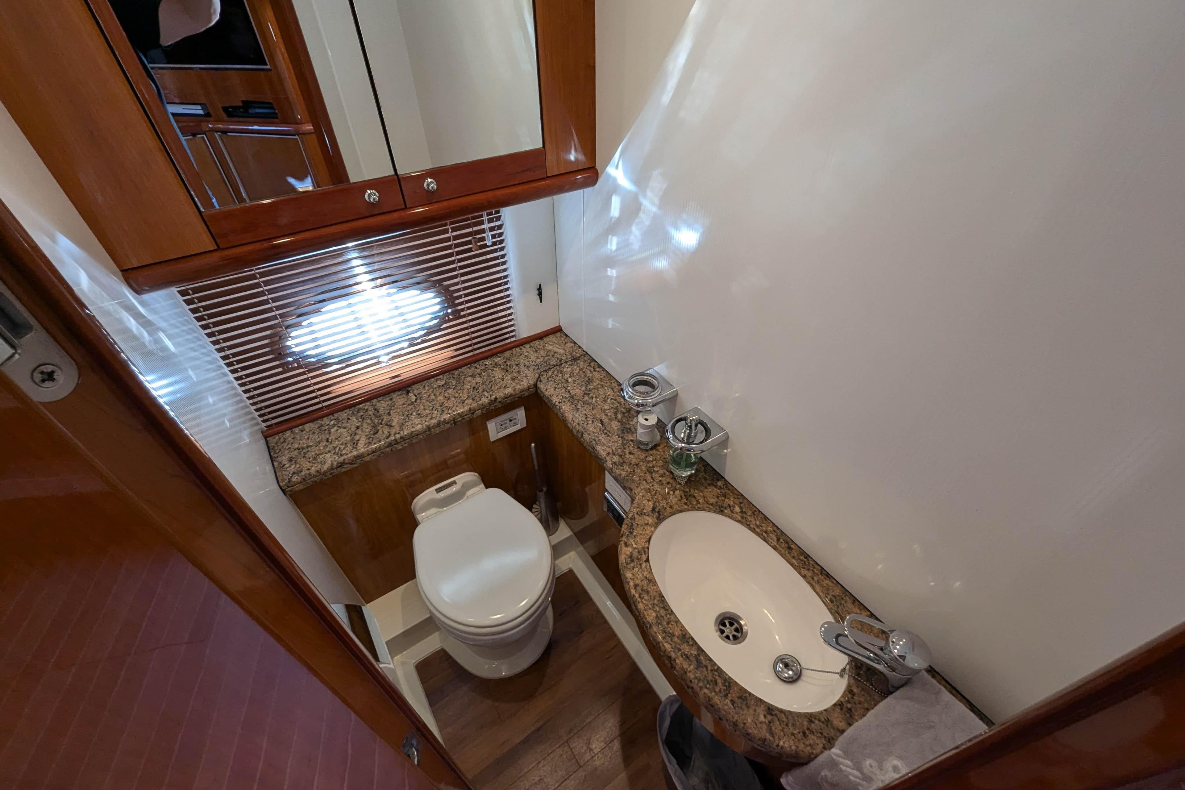 Luxurious bathroom in 2006 Sunseeker Predator 68 yacht with granite countertop and wooden accents.