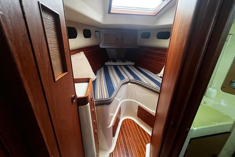 Interior of a 1980 CS 36 Traditional sailboat with striped bedding and wooden accents.