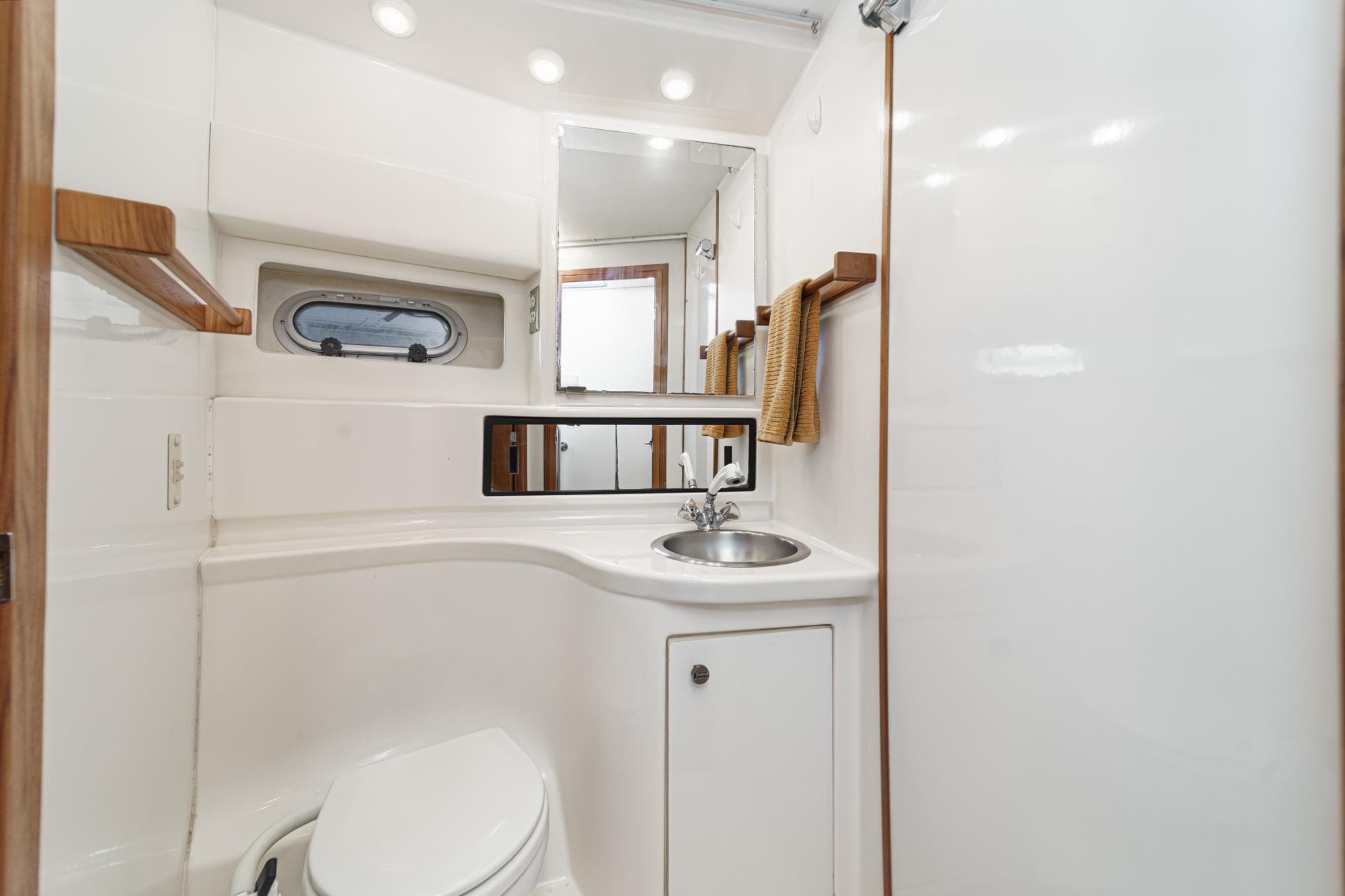 1998 Bayliner 3988 Motoryacht bathroom with sink, toilet, mirror, and porthole window.
