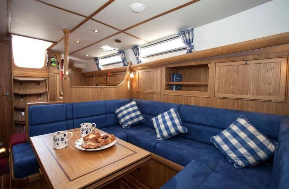 Interior of 2025 Rustler 37 yacht with blue seating and wooden accents.