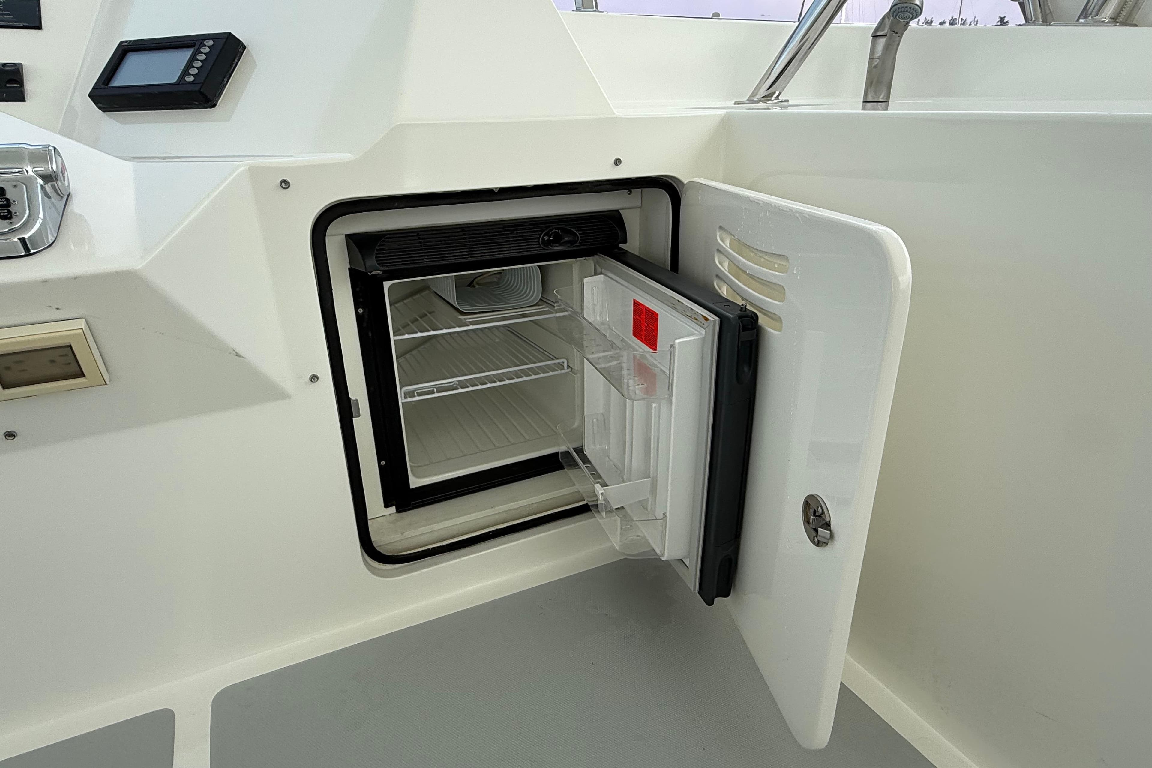 Open mini fridge on 2009 Nordhavn N64 yacht, showcasing interior shelves and controls.